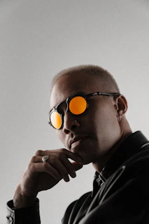 Man wearing sunglasses with orange lenses and thoughtful pose