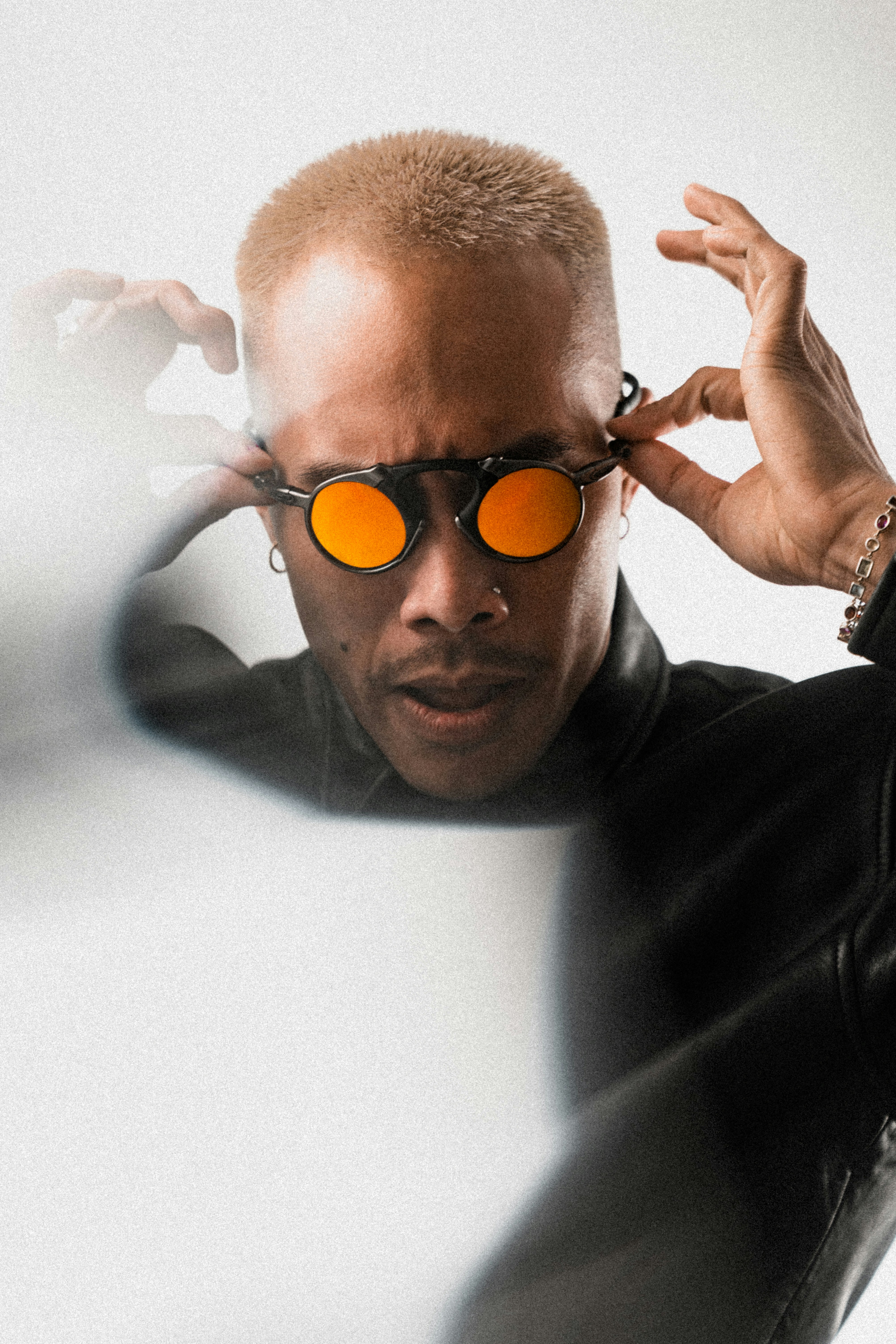 Man with orange sunglasses adjusts eyewear