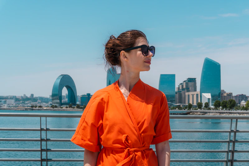 curvy woman in orange dress by waterfront cityscape