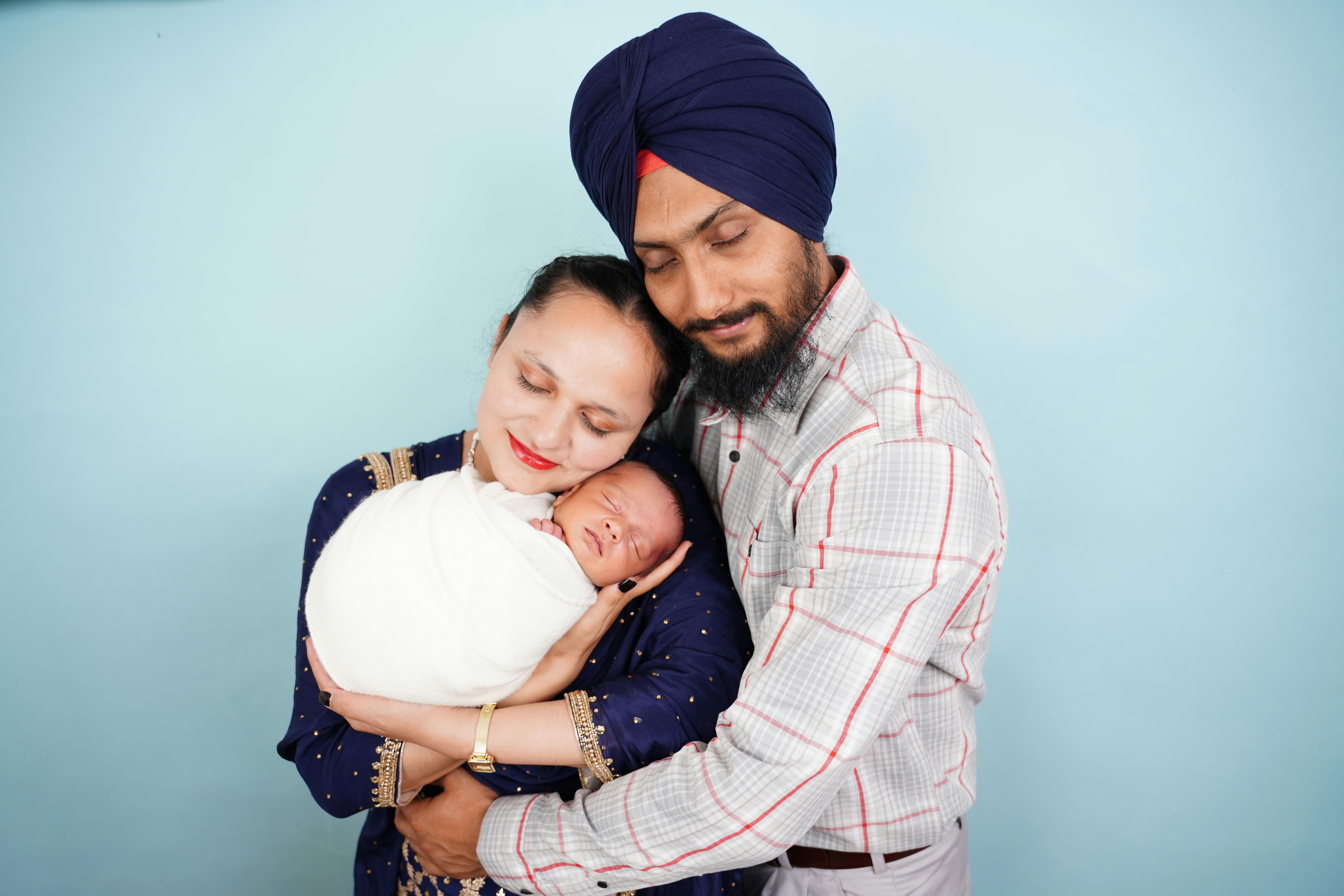 Parents holding their newborn baby wrapped in white.
