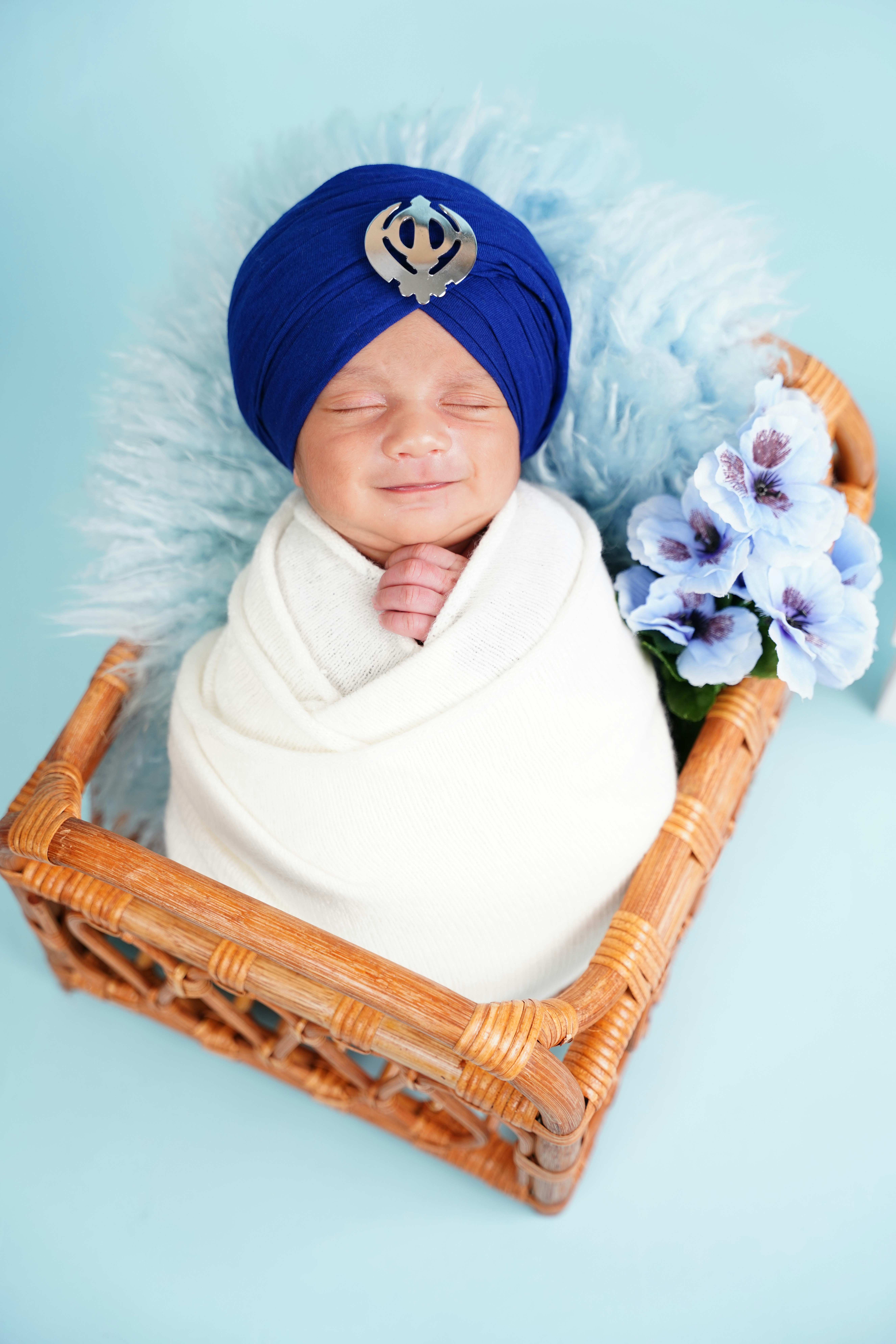 Newborn baby in a blue turban rests in a basket