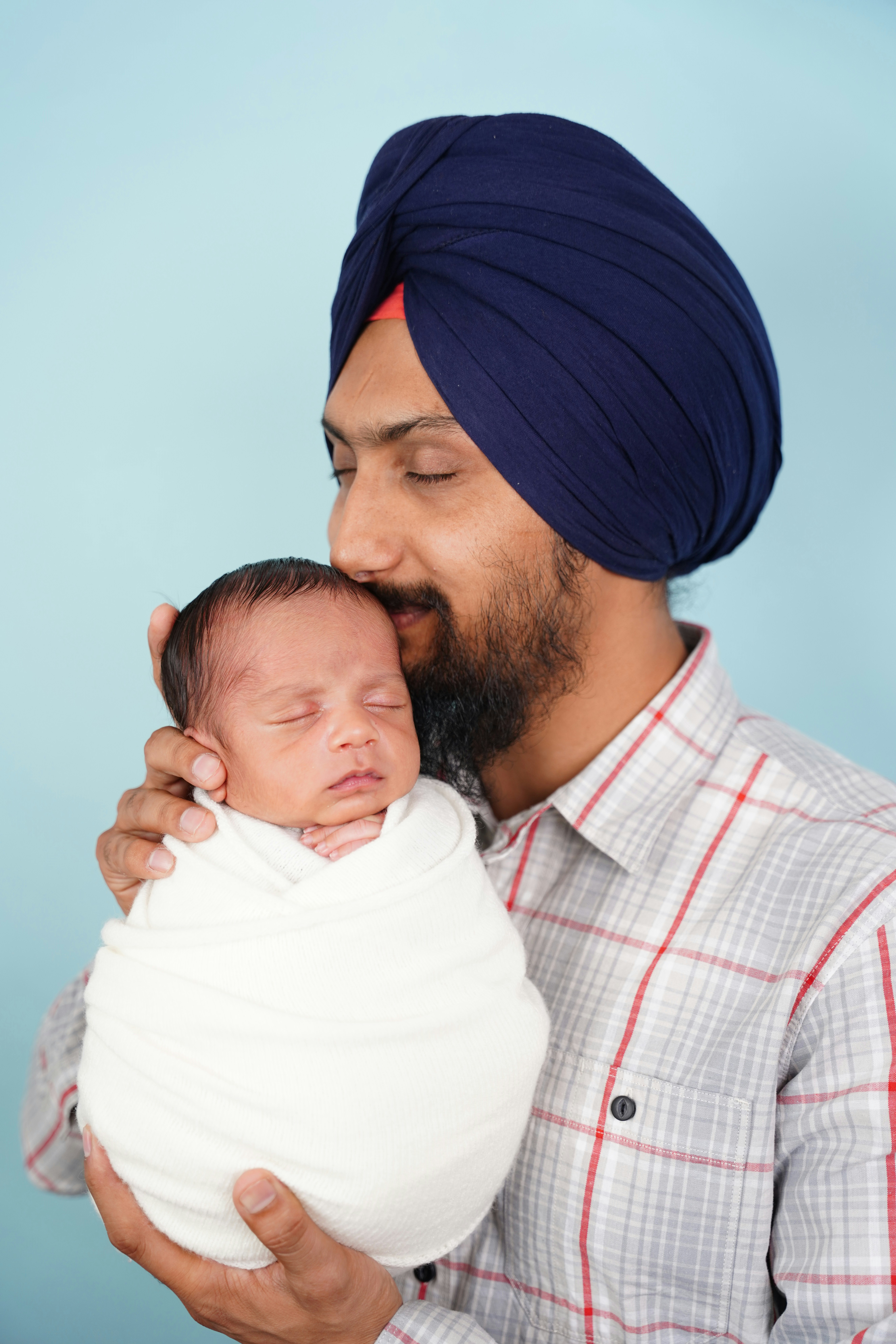 Father kissing his newborn baby wrapped in white