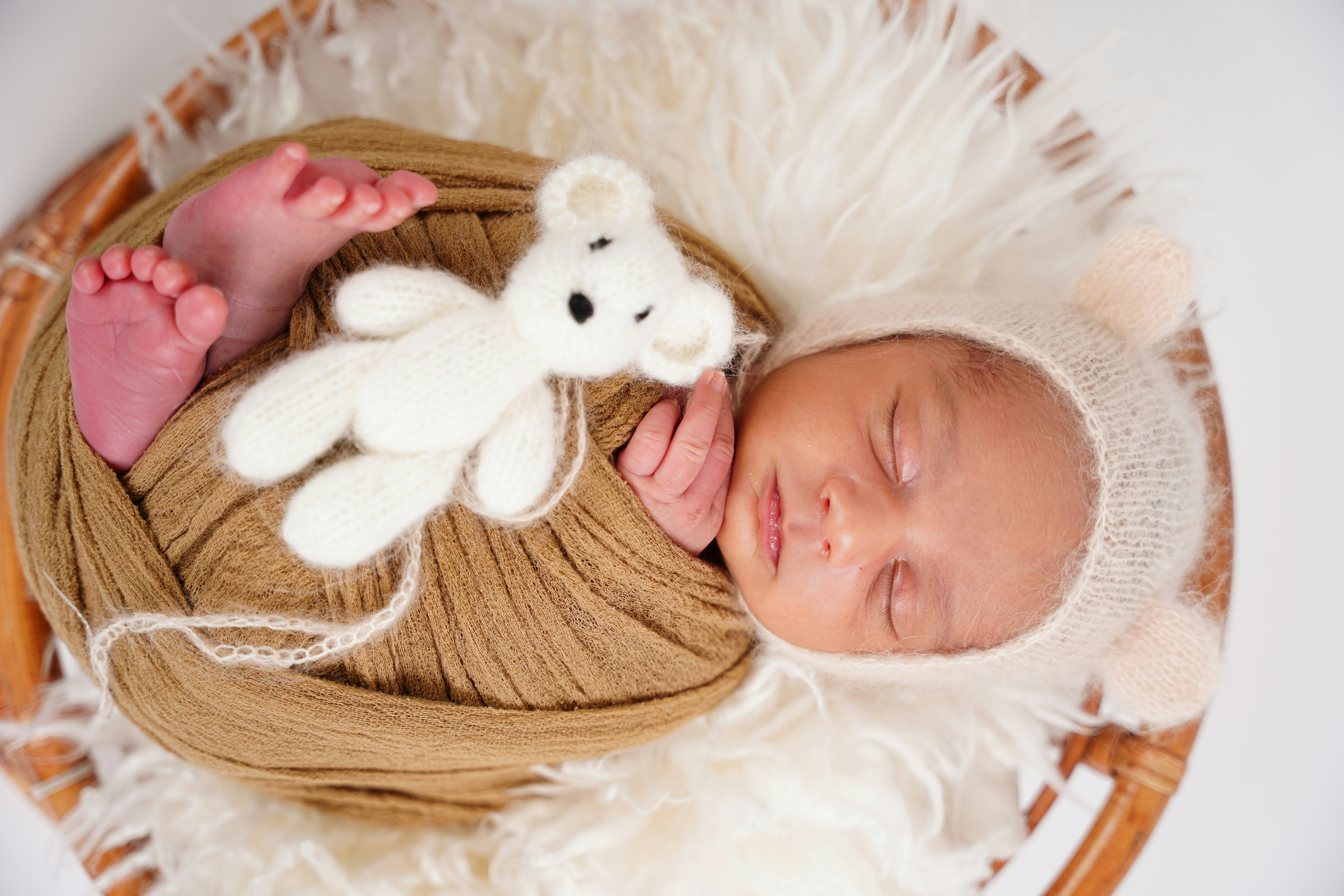 Newborn baby sleeping with a teddy bear.