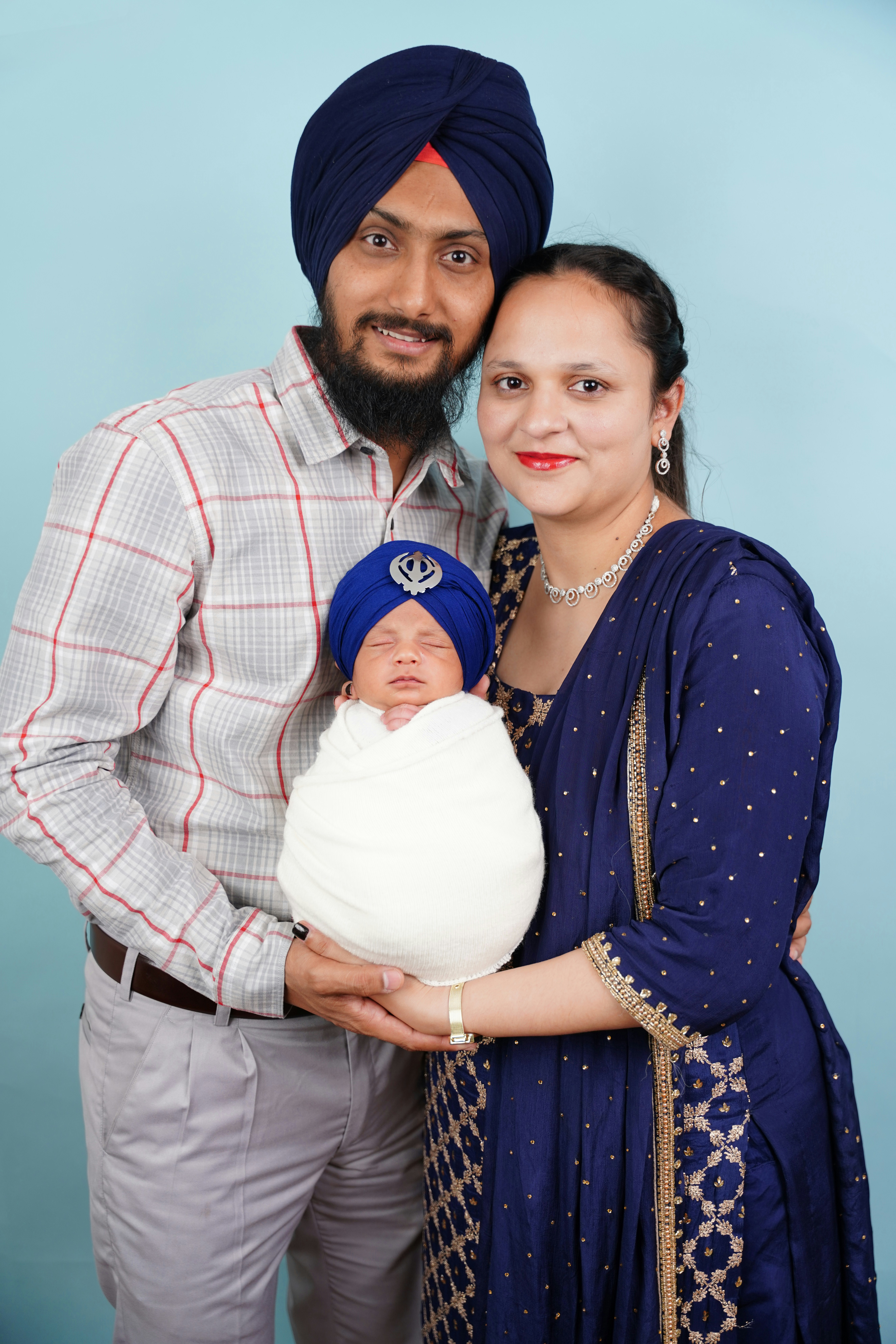 Sikh parents holding their newborn baby wearing a turban