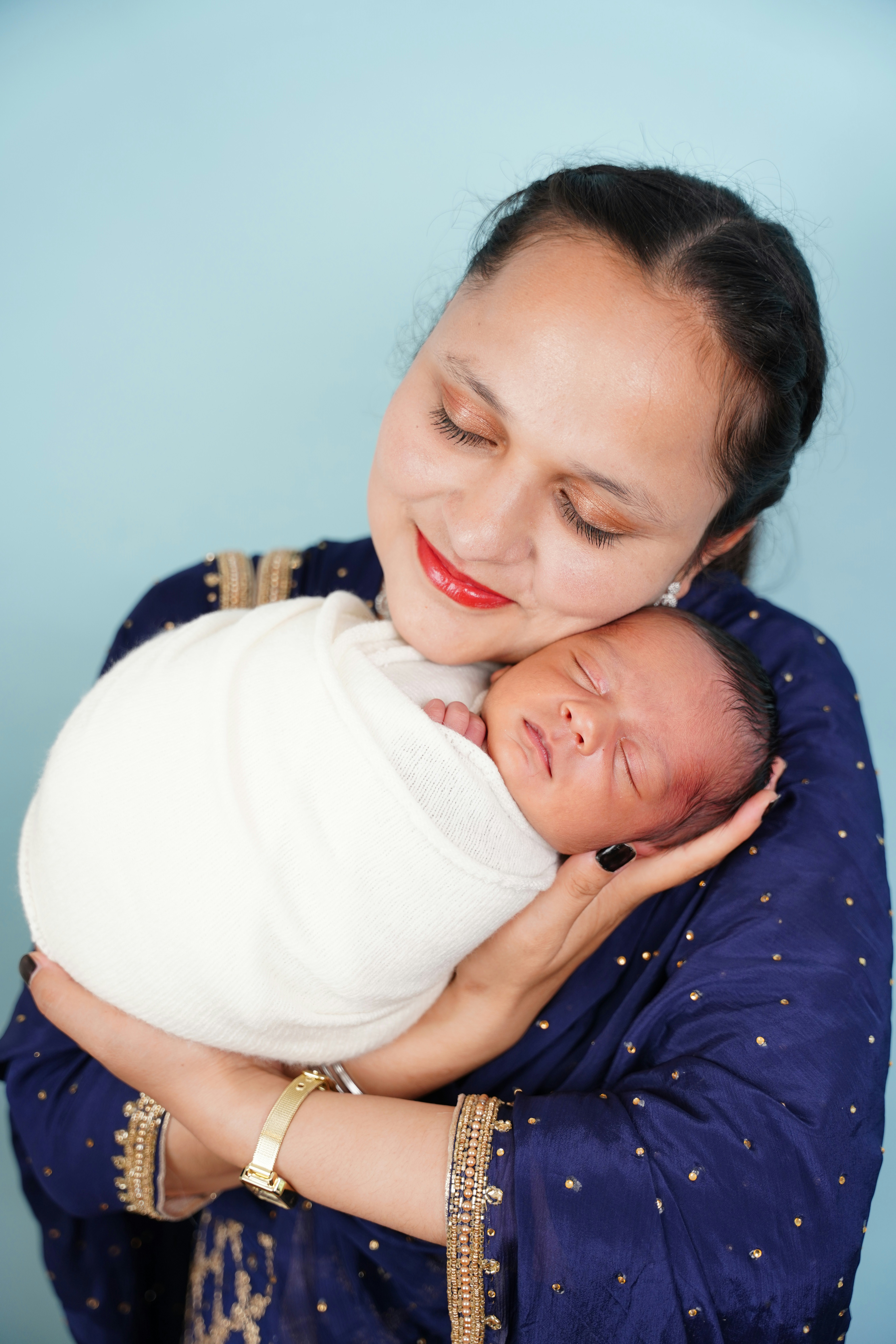 Mother holding her newborn baby wrapped in white