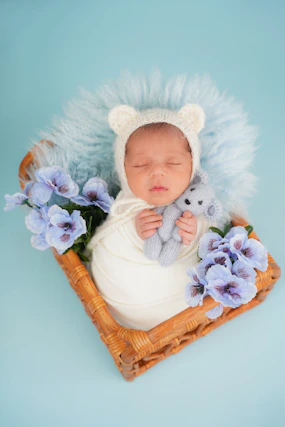 Newborn baby sleeping in basket with teddy bear