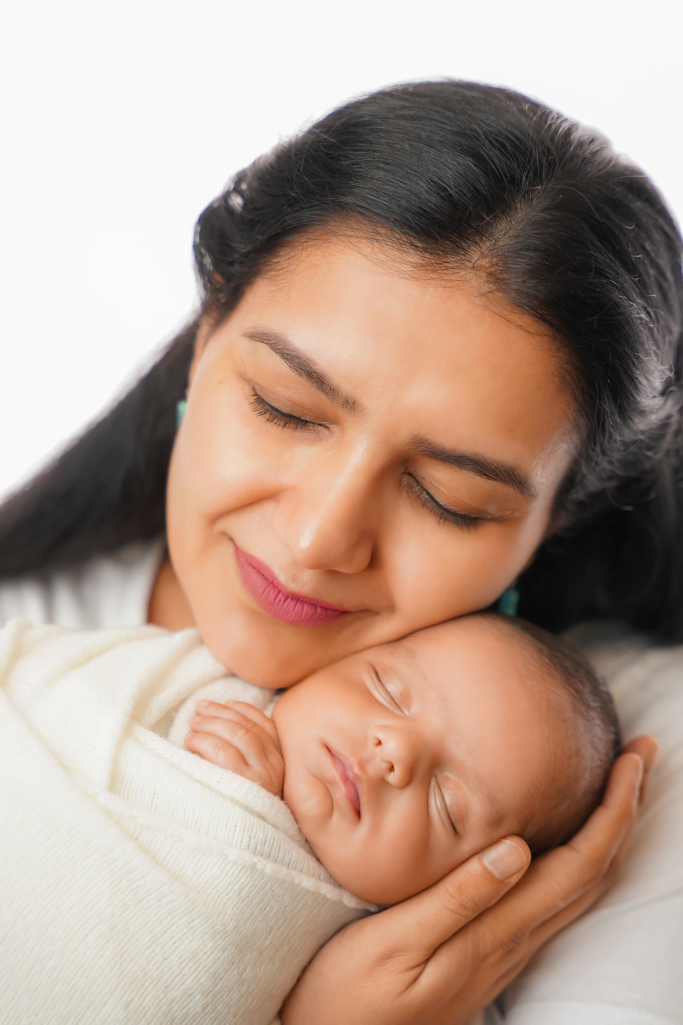 Mother gently holding her sleeping newborn in a soft neutral setting