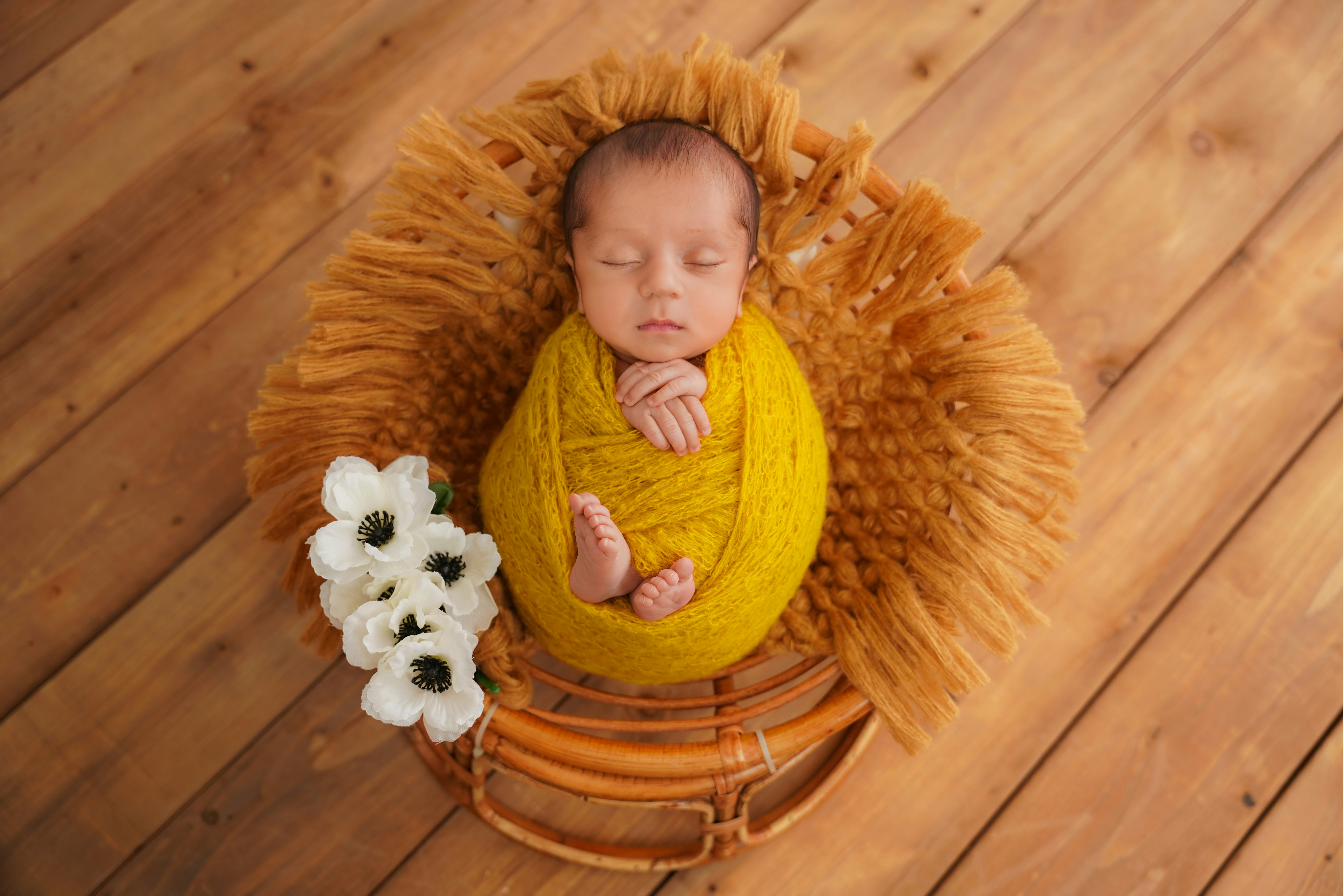 Newborn baby sleeping wrapped in yellow blanket.