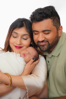 Parents lovingly holding their newborn baby wrapped in a blanket.