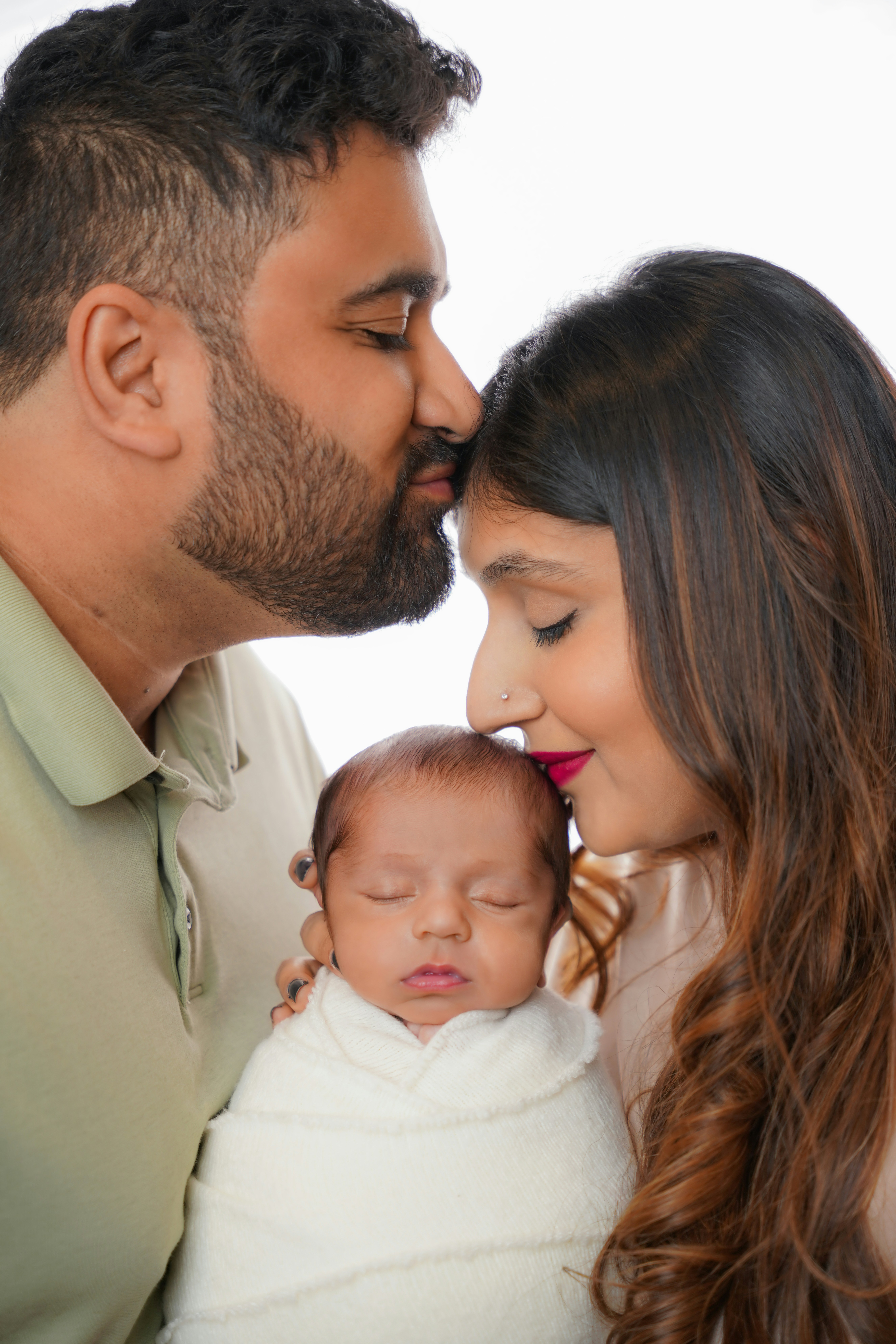 Eltern küssen ihr Neugeborenes