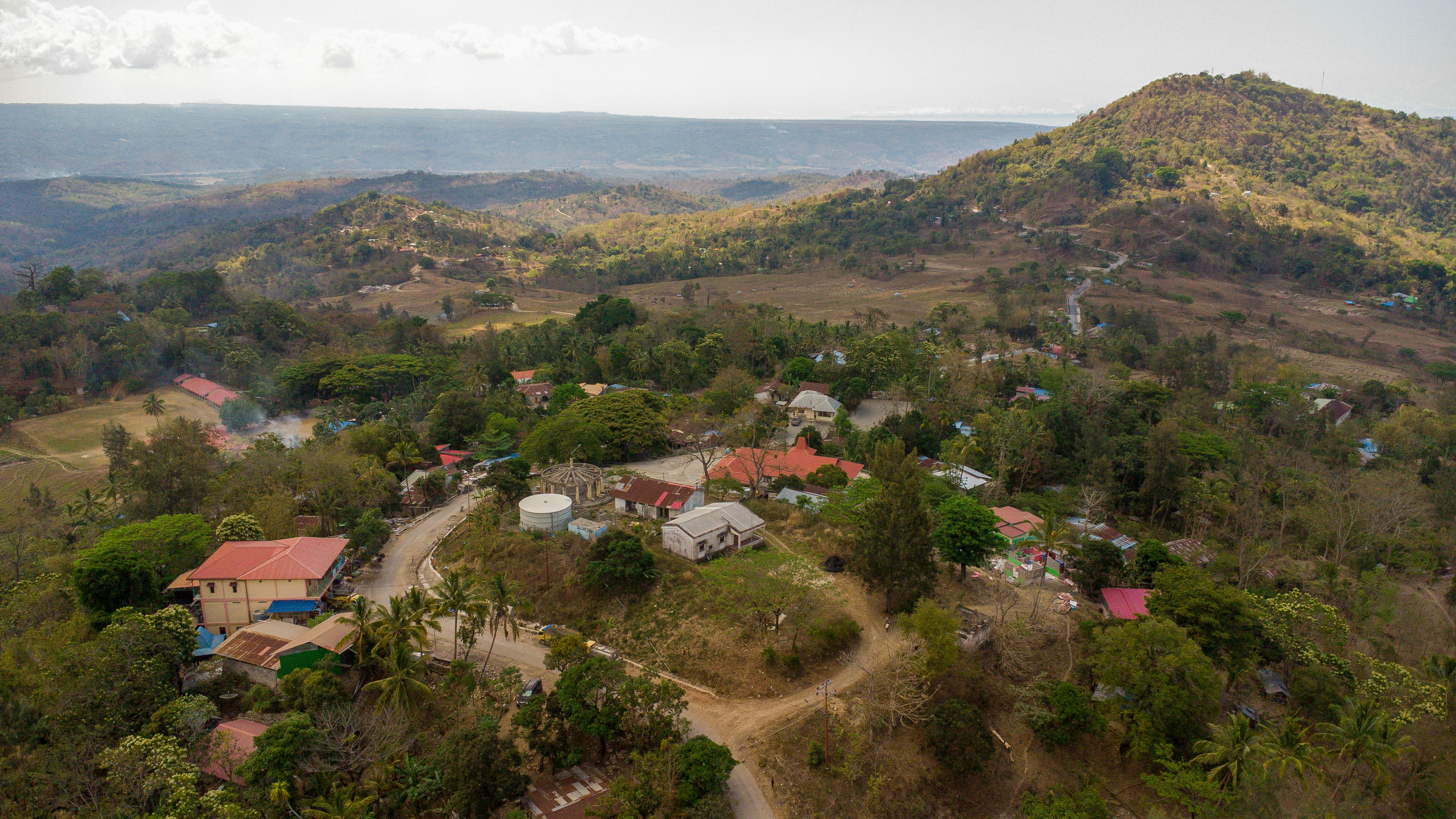Aerial view of a small village nestled in rolling hills.