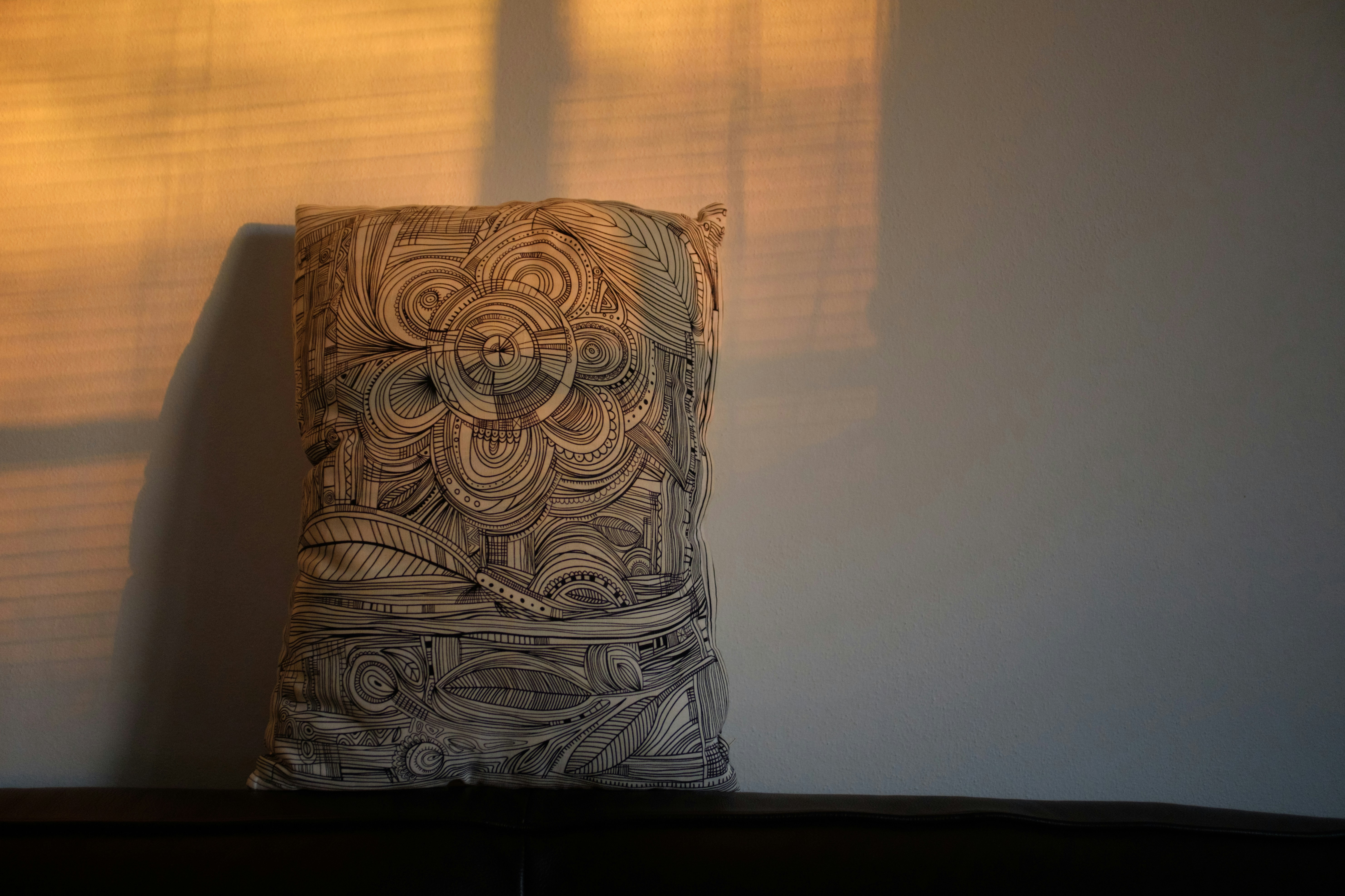 A decorative pillow with intricate patterns on a shelf.