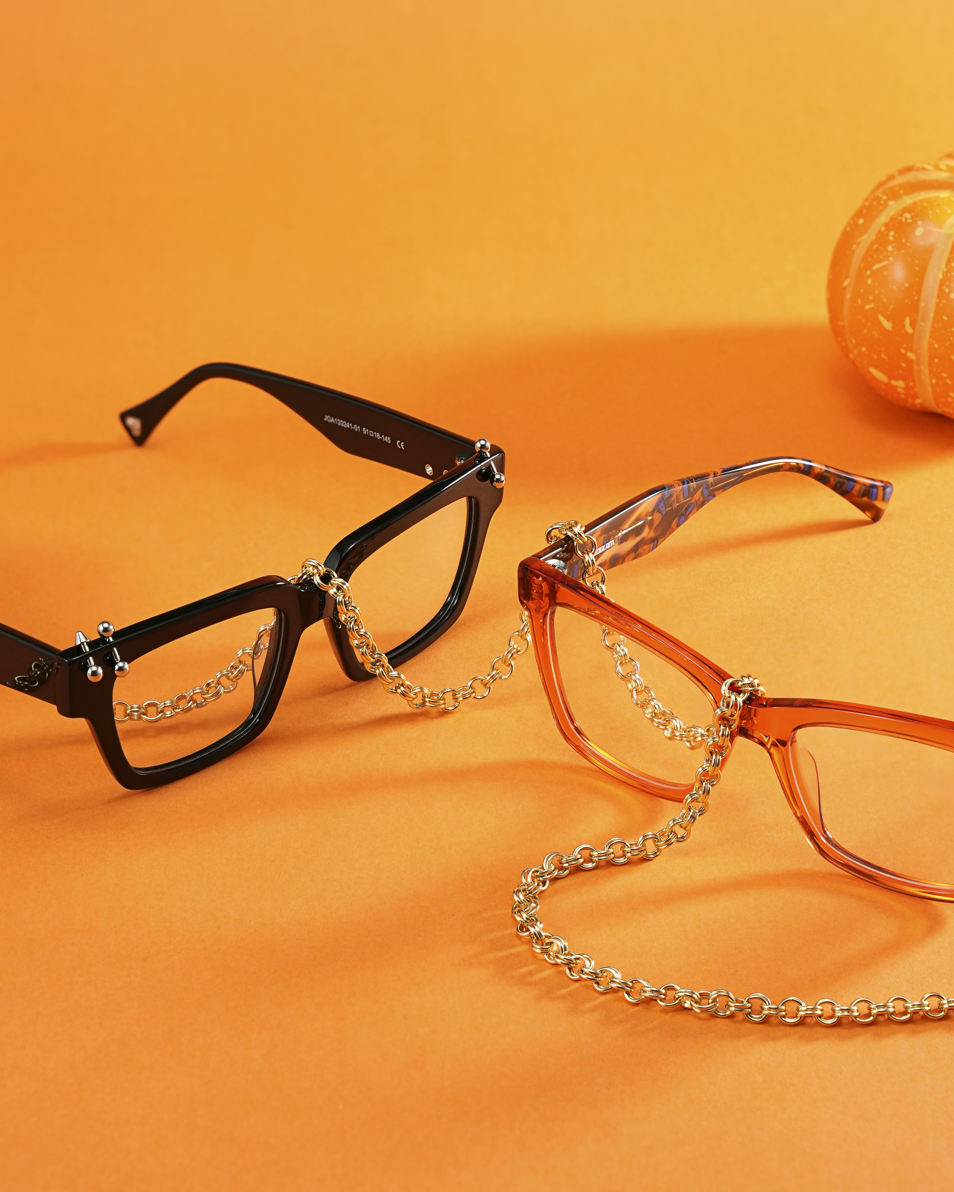 オレンジ色の背景にチェーンが付いた2組のメガネ