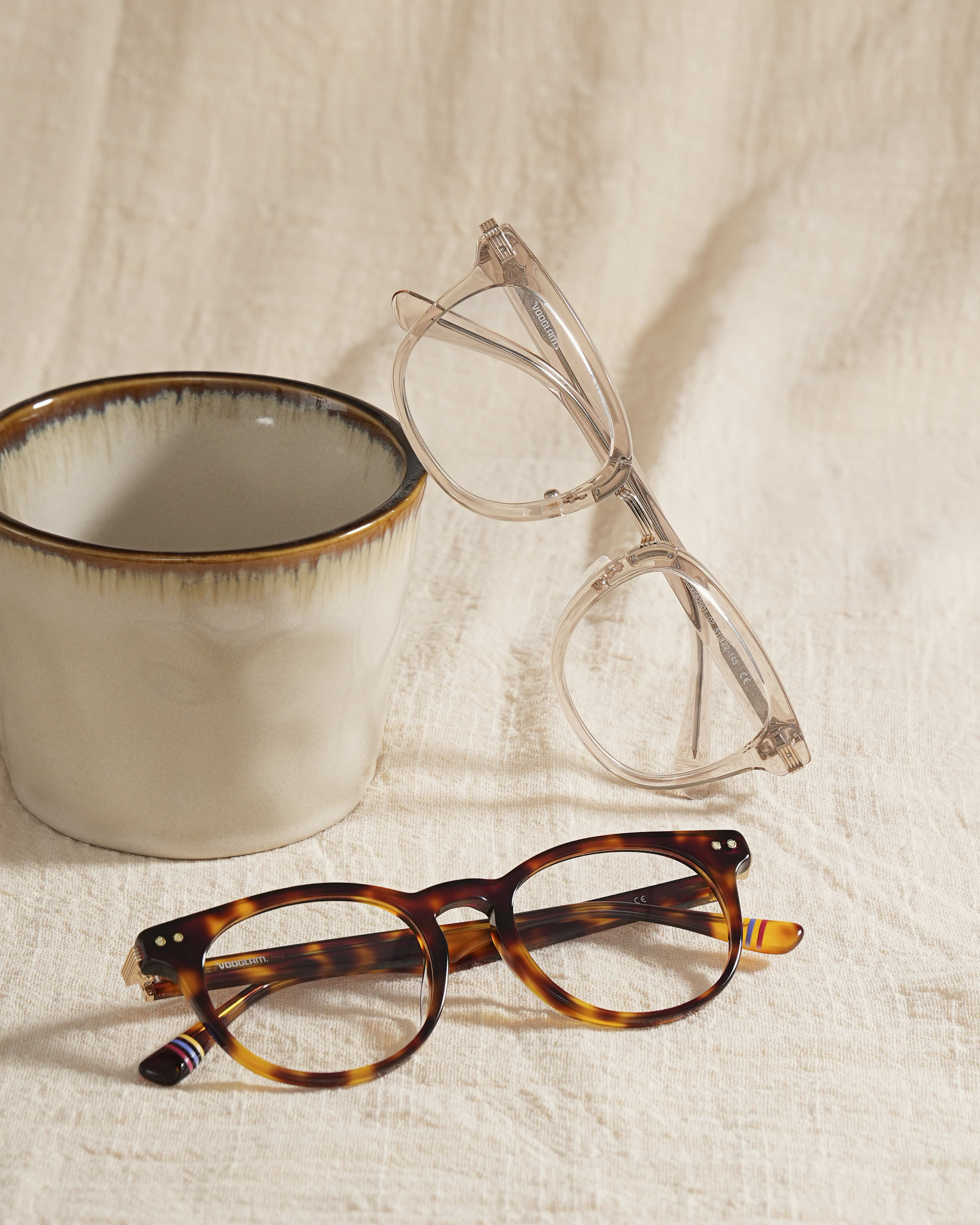 Deux paires de lunettes acétate posées sur lin écru, ambiance café de quartier
