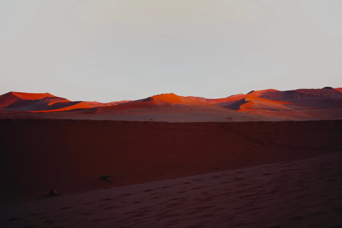 Towering rust-red sand dunes glowing at sunrise in the Namib Desert at Sossusvlei, Namibia