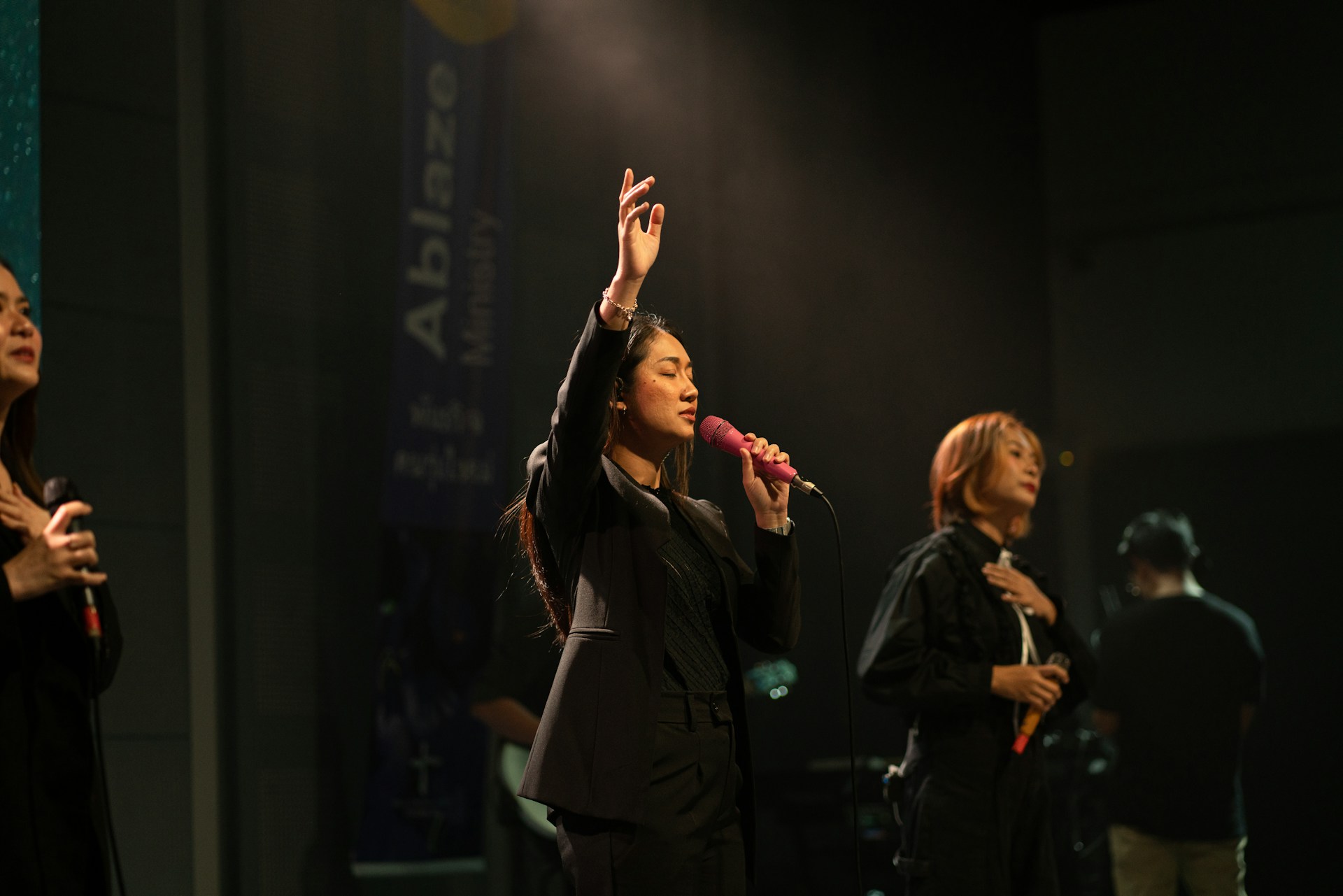 A woman sings into a microphone on stage.