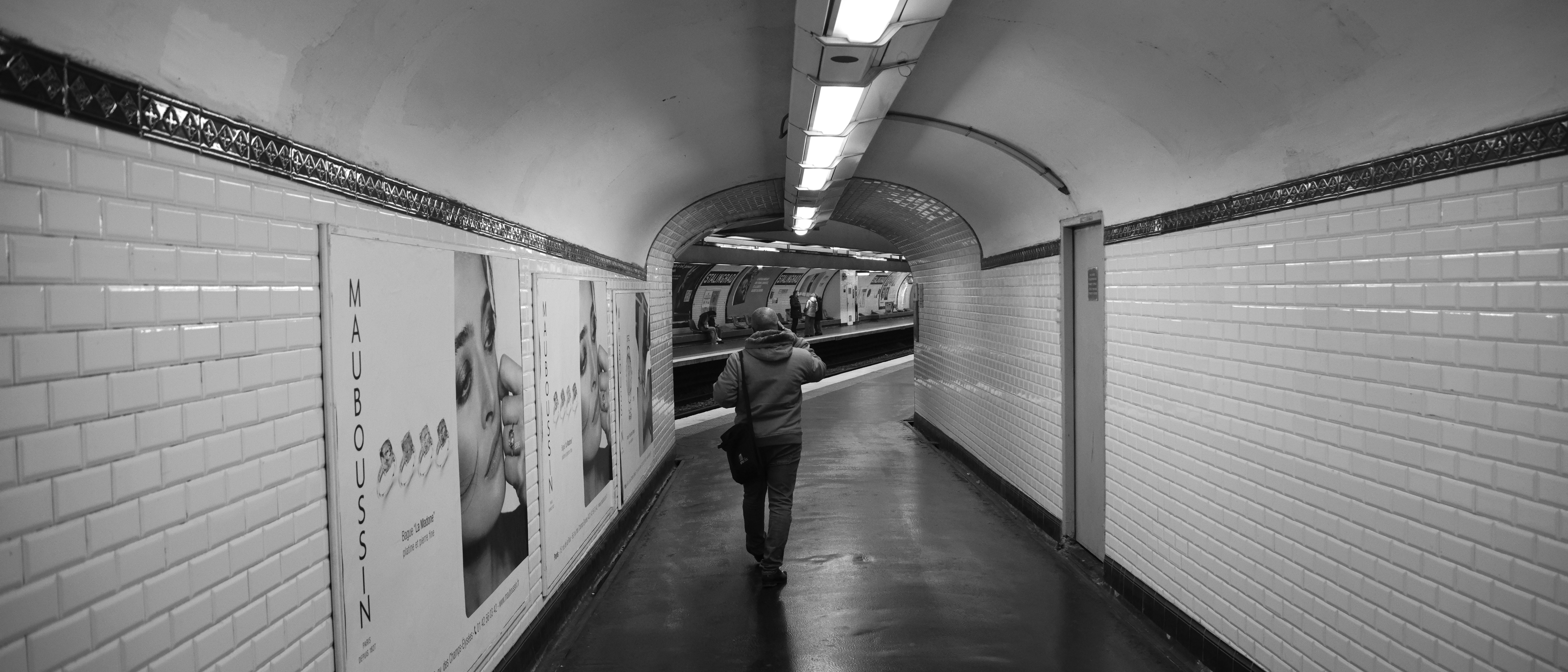 Person walks down a tiled subway tunnel