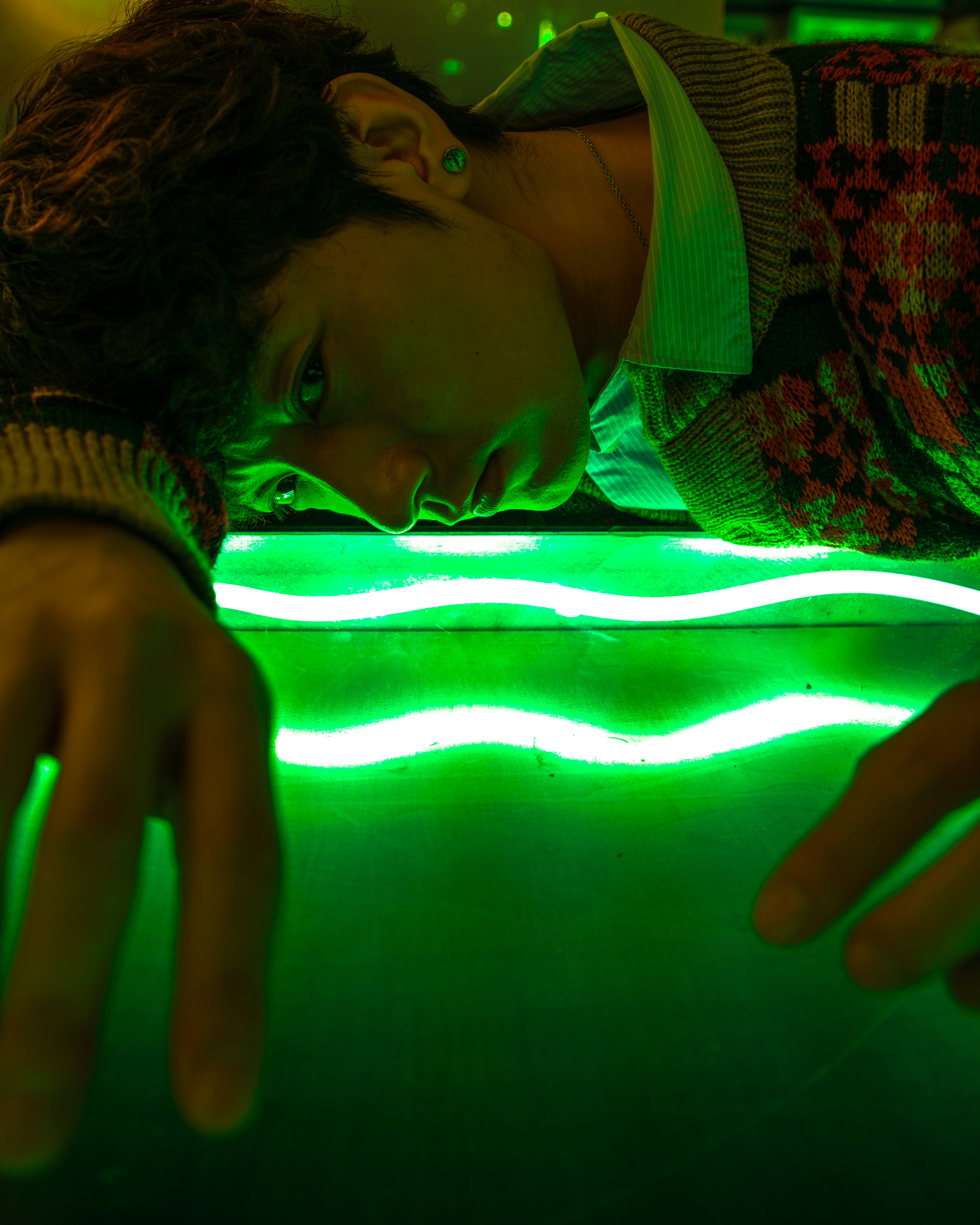 Man leaning over a glowing green surface.