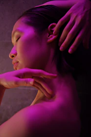 Woman with hands touching her neck under purple light