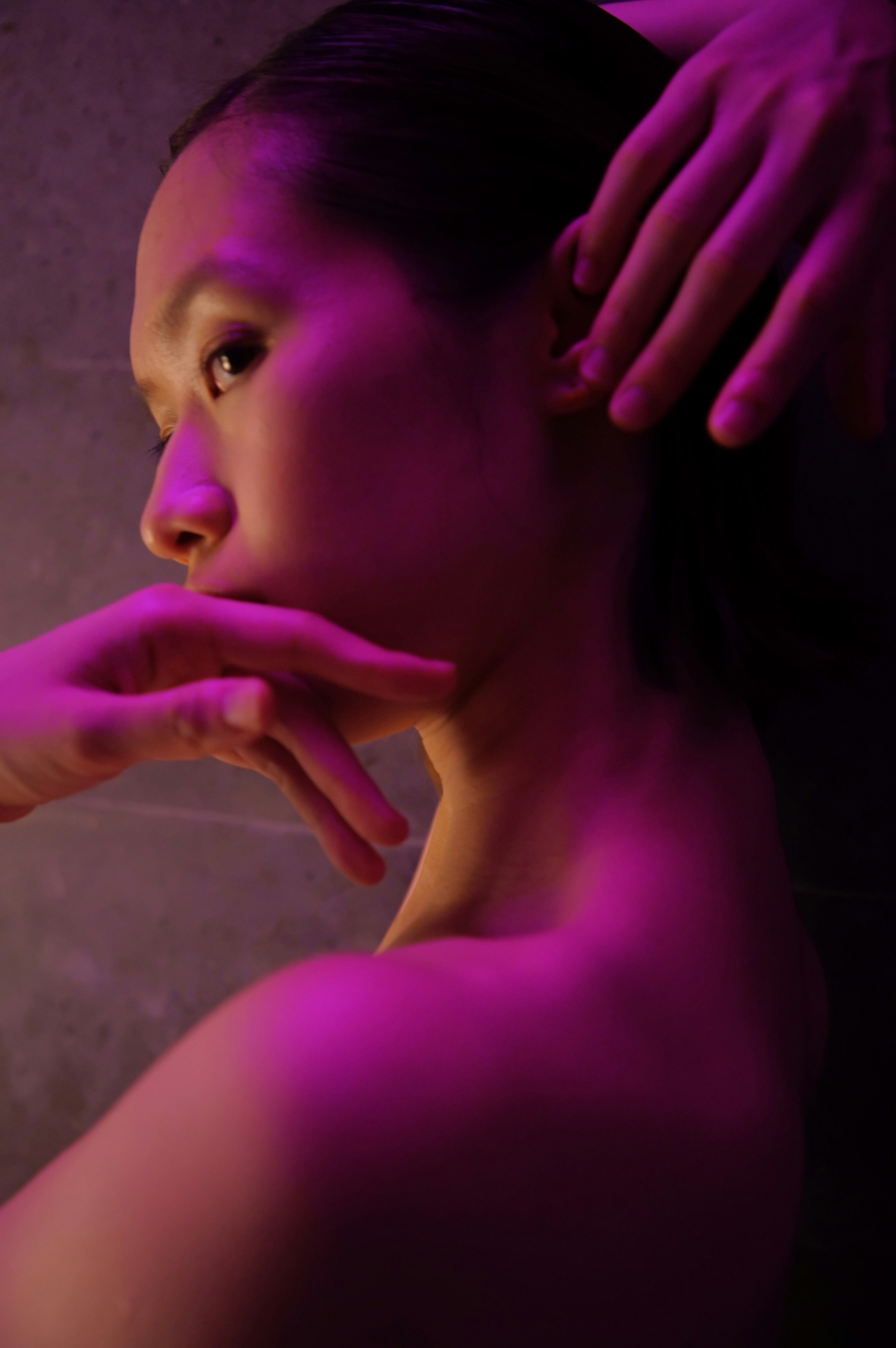 Woman with hands touching face in purple light