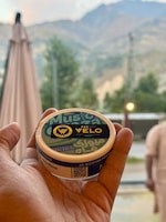 Hand holding a velo nicotine pouch container outdoors