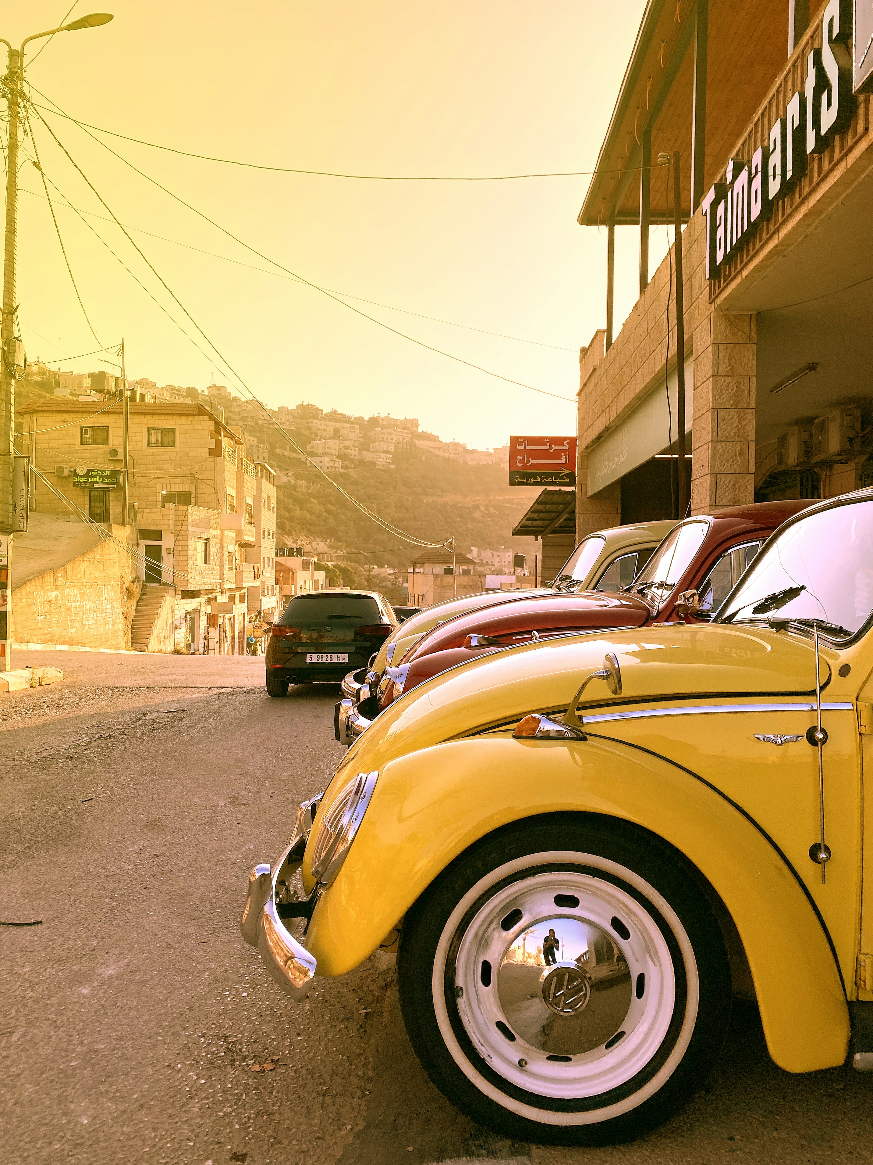 Coches clásicos amarillos y rojos aparcados en la calle.
