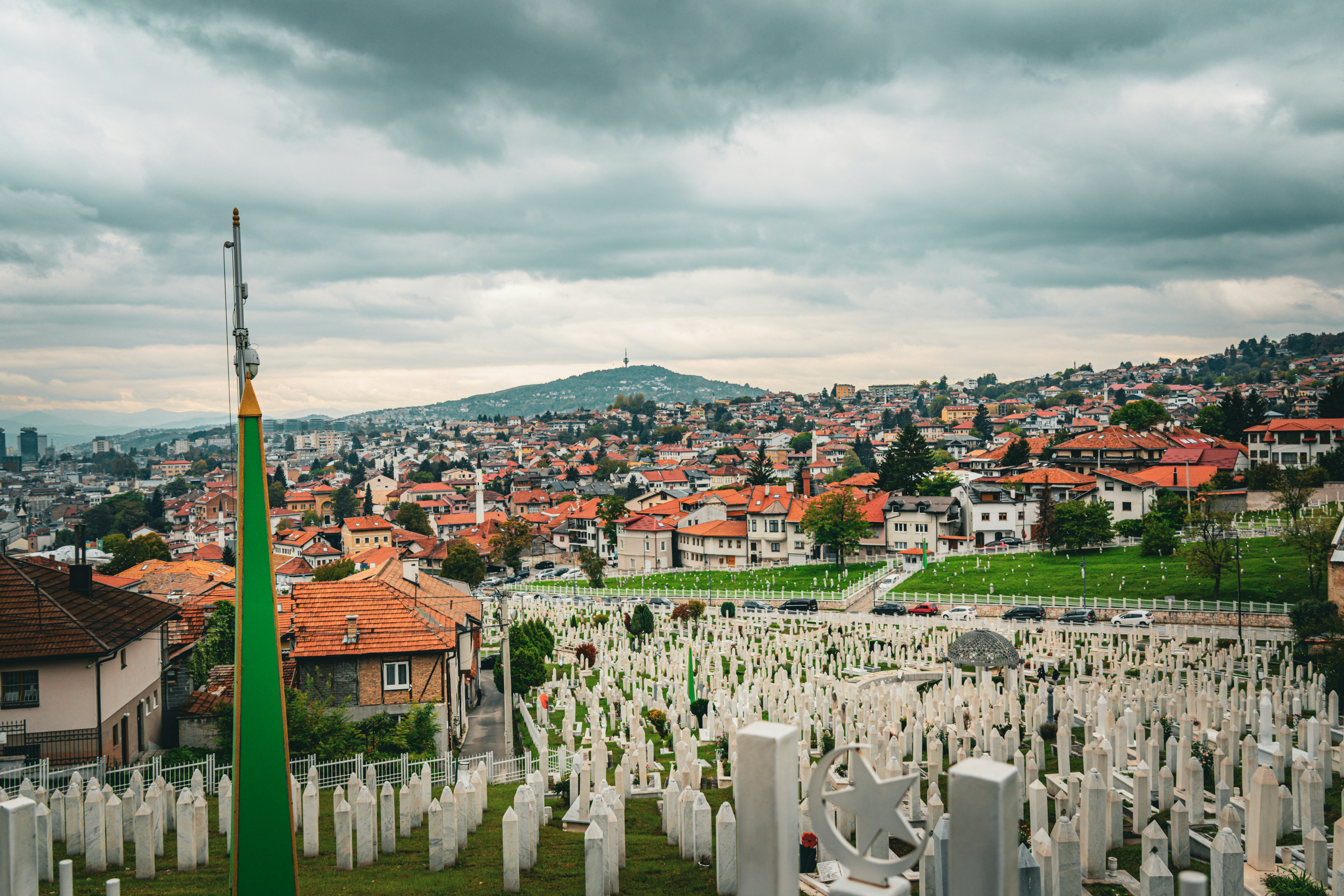 White gravestones in a cemetery with a city background.