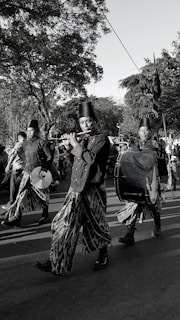 Musicians in traditional attire play instruments during a parade.