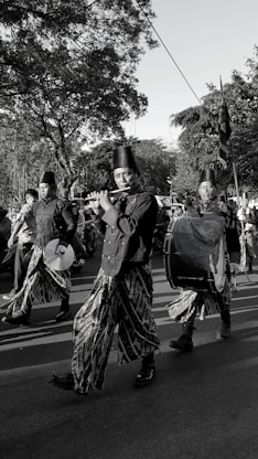 Musicians in traditional attire play instruments during a parade.