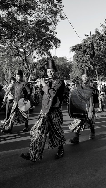 Musicians in traditional attire play instruments during a parade.