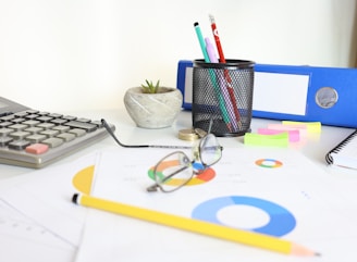 Desk with calculator, glasses, charts, and office supplies