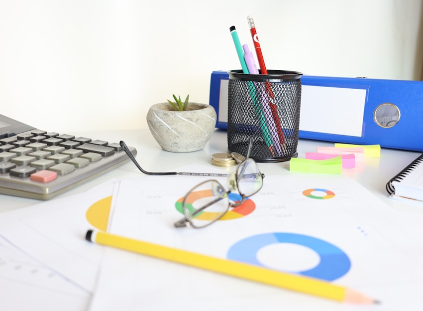 Desk with calculator, glasses, charts, and office supplies
