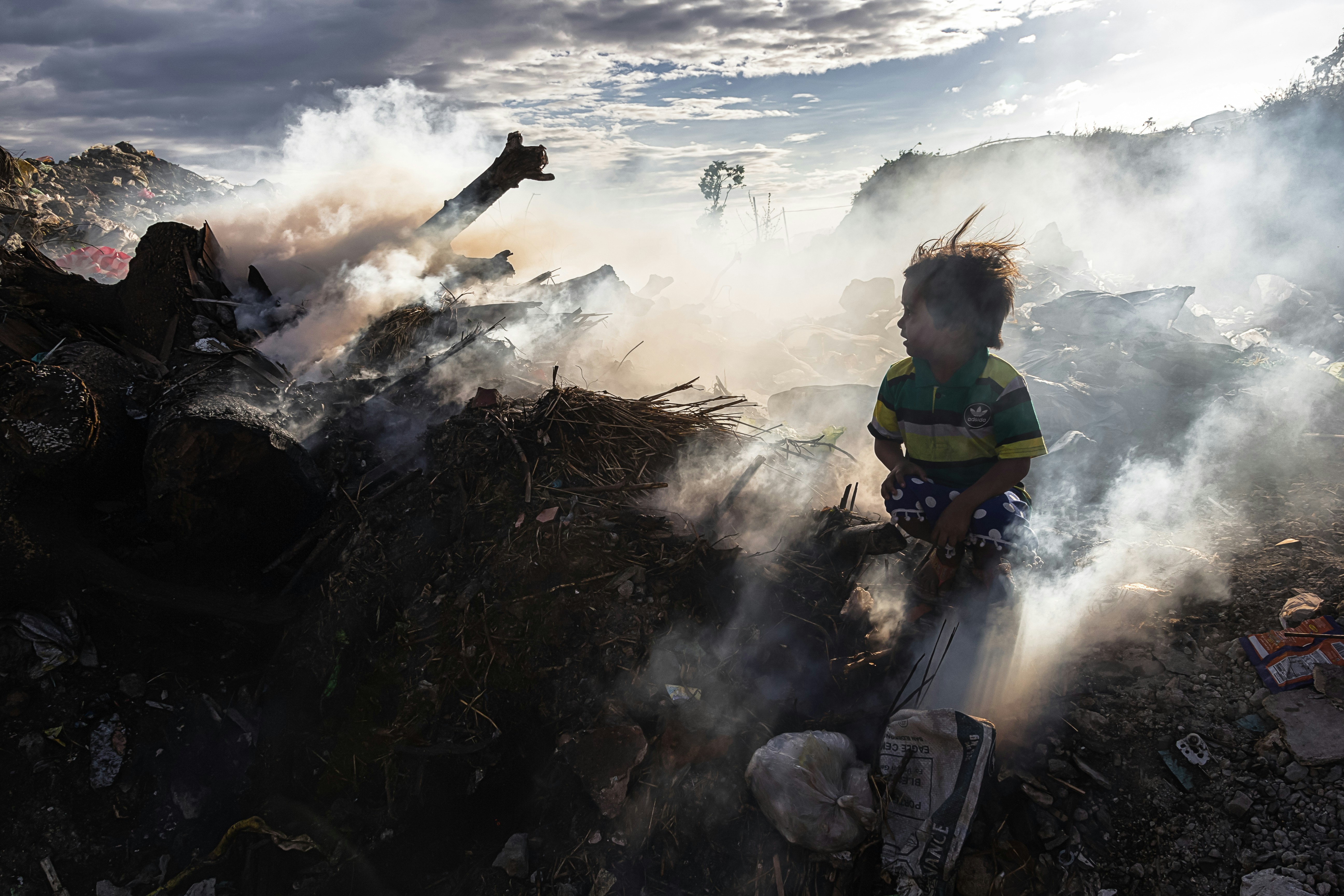 Child sits amidst smoke and debris