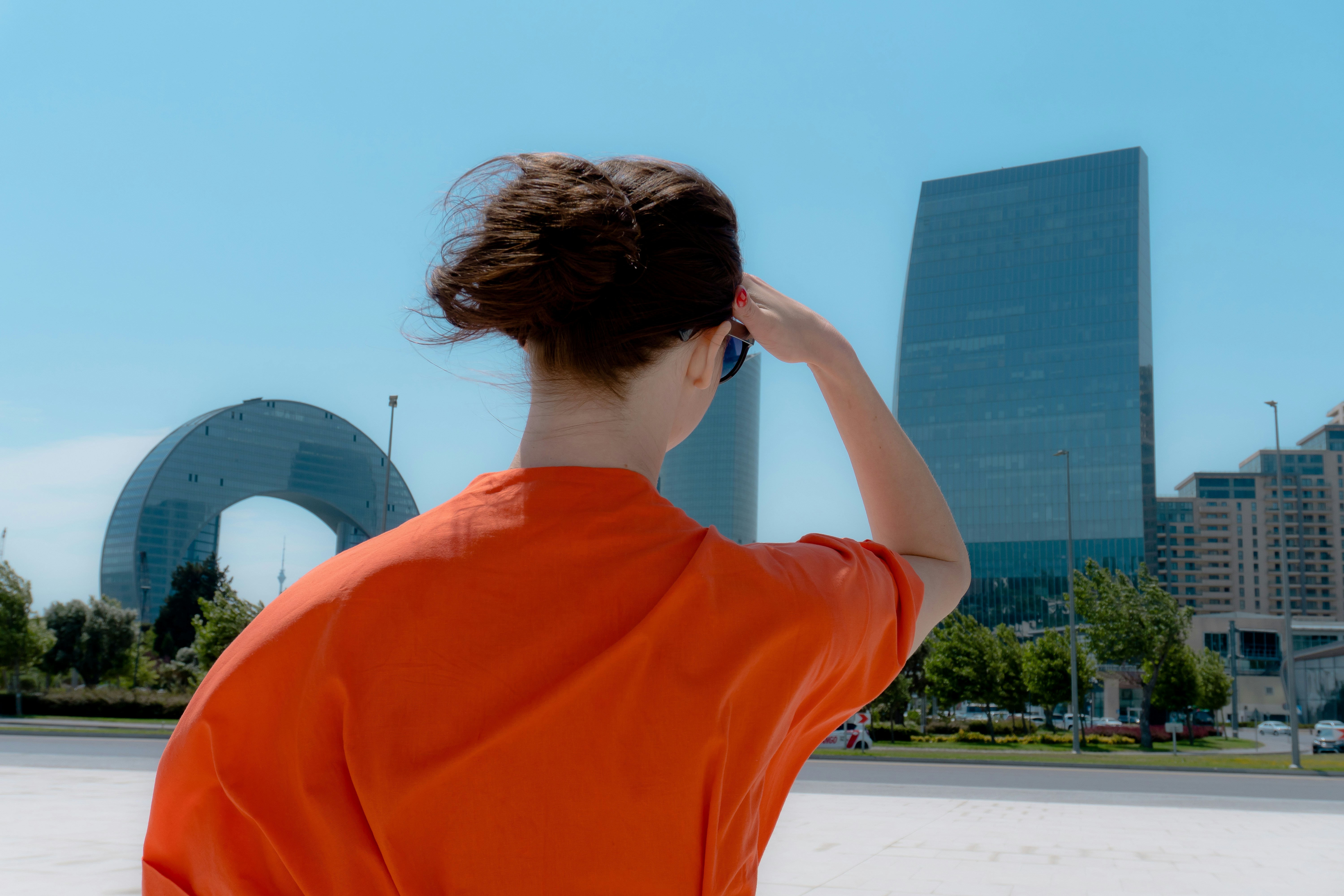 Woman in orange shirt looking at modern buildings