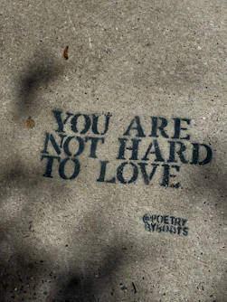 Text on concrete reads "you are not hard to love."