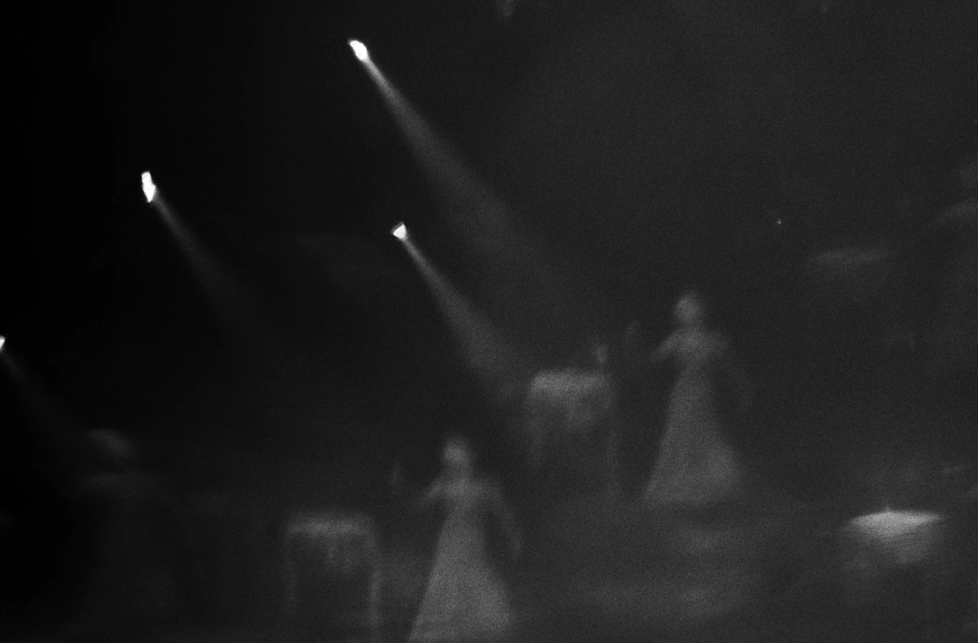 Performers illuminated by spotlights on a dark stage.