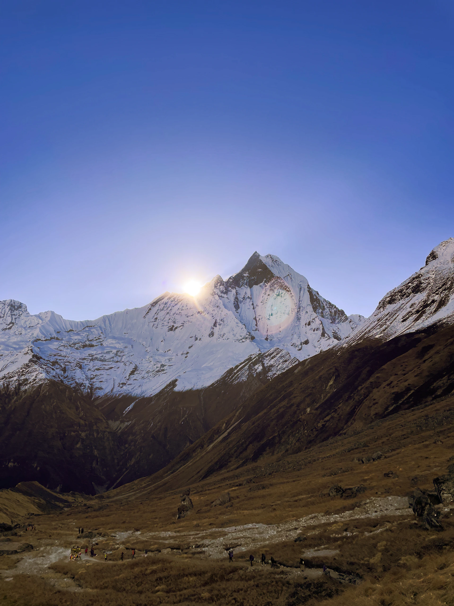 Sun setting behind snow-capped mountain peak.