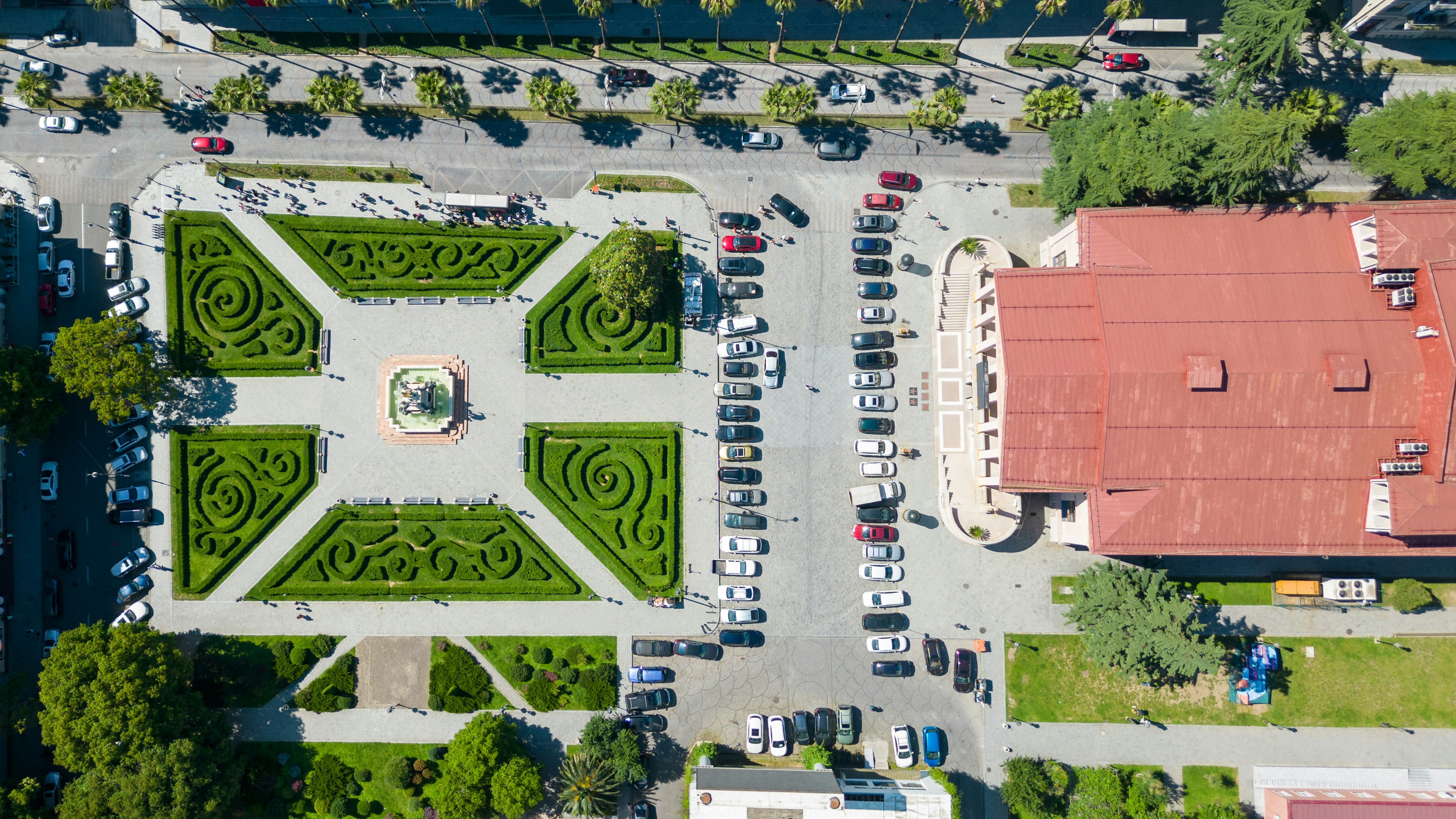 Aerial view of a formal garden with cars parked nearby.