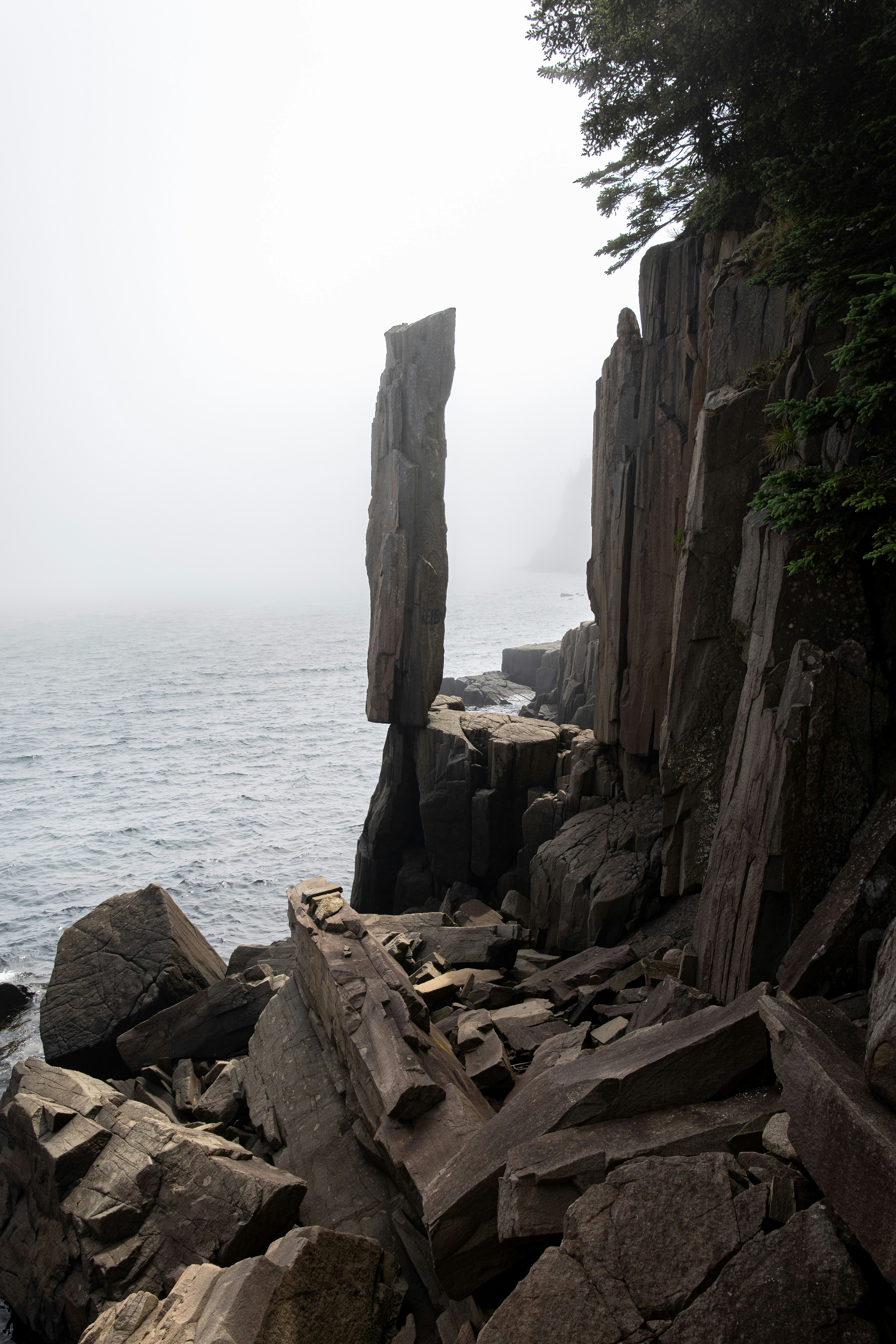 Tall rock balanced precariously on a cliff by the sea