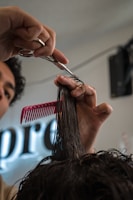 Barber cutting hair with scissors and comb