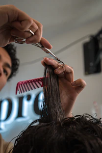 Barber cutting hair with scissors and comb