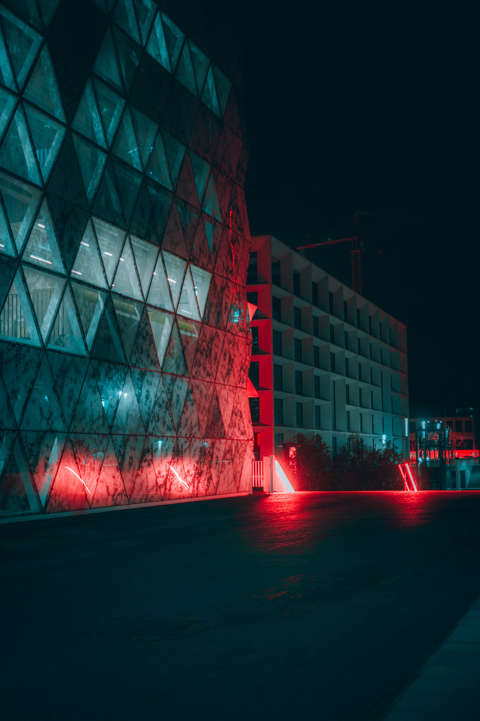 A faceted building lit red and teal at night