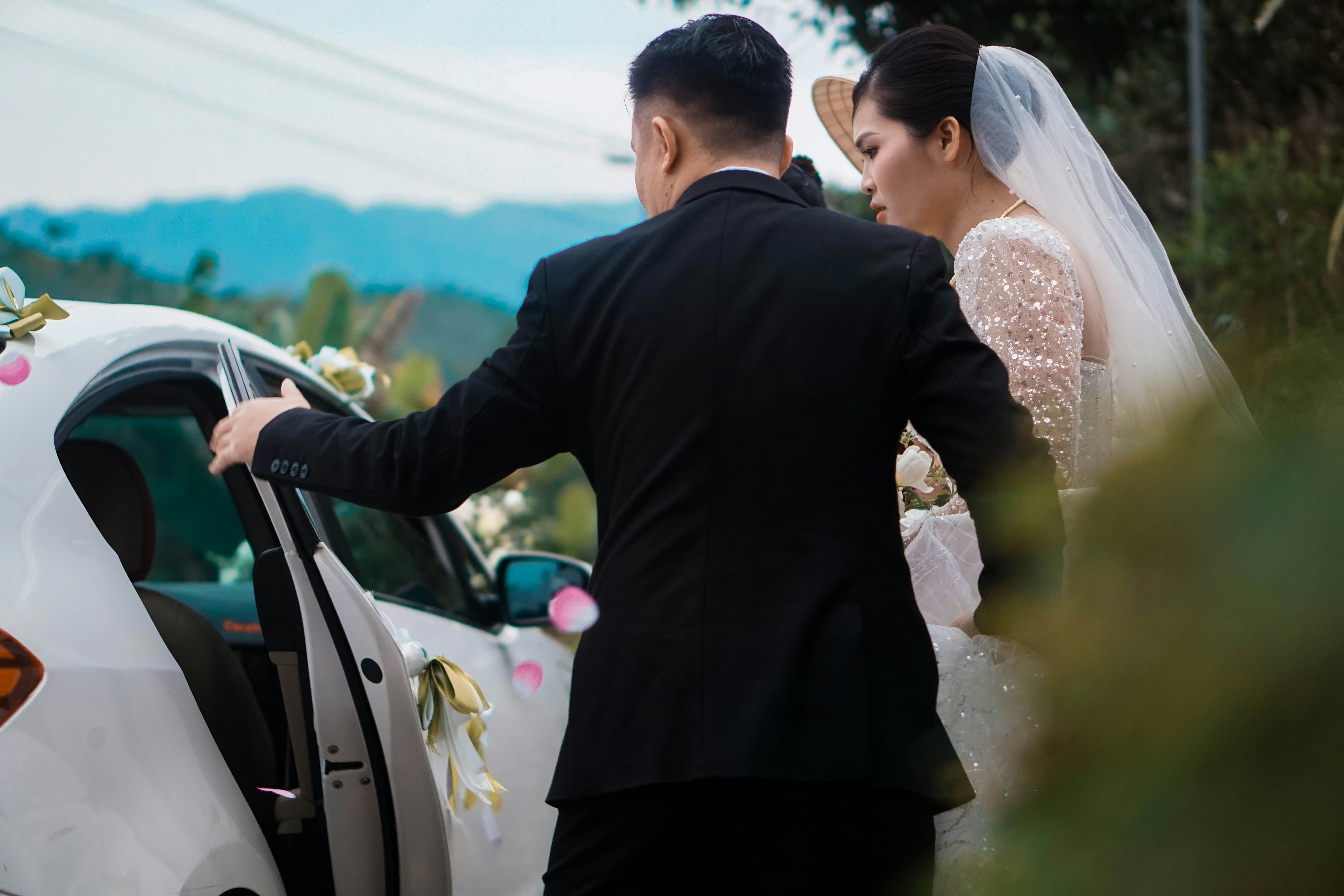 Bride and groom entering a decorated wedding car