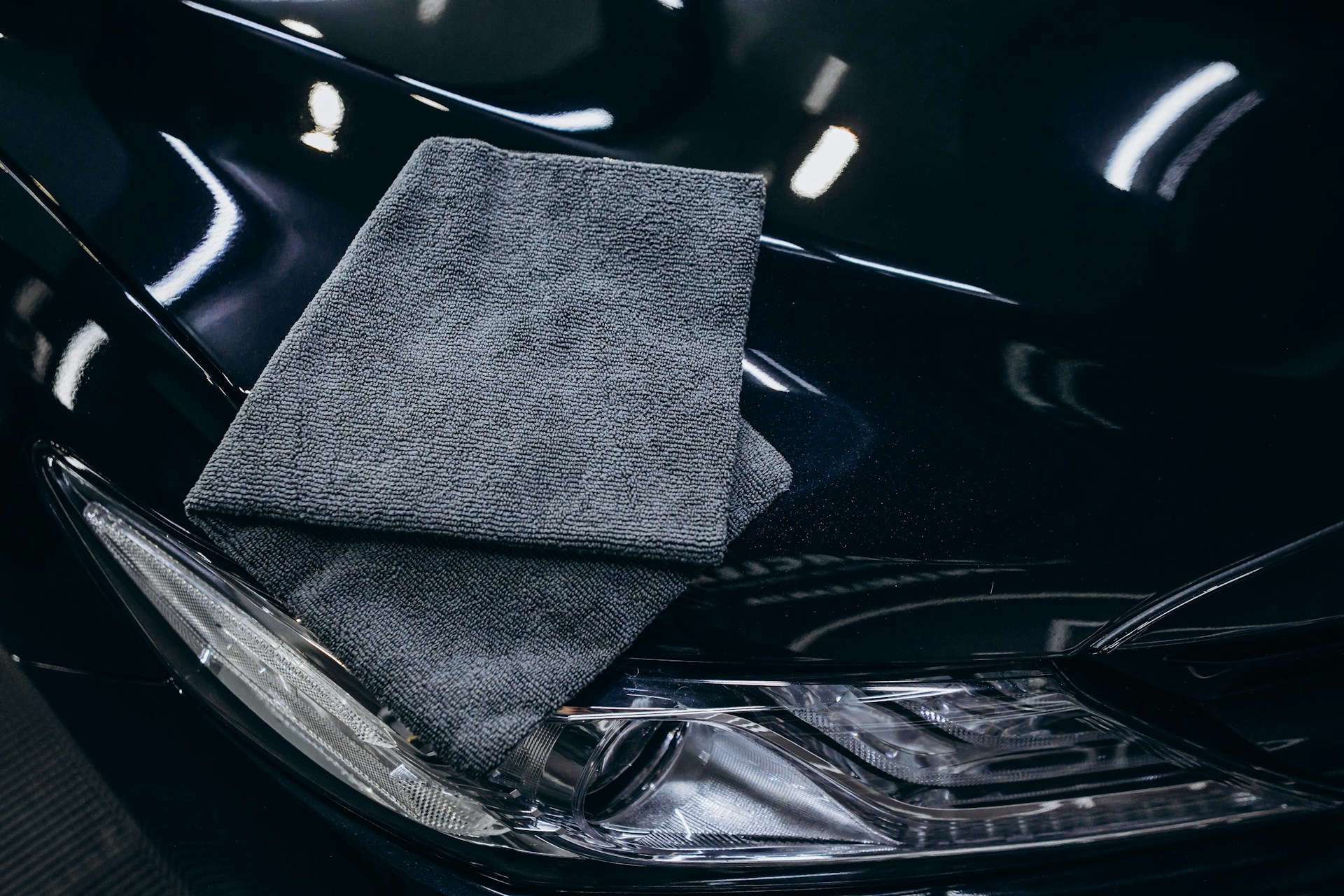 Gray microfiber cloth on a black car hood.