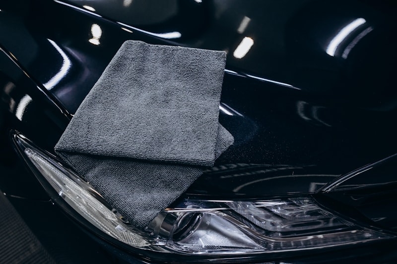 Gray microfiber cloth on a black car hood.