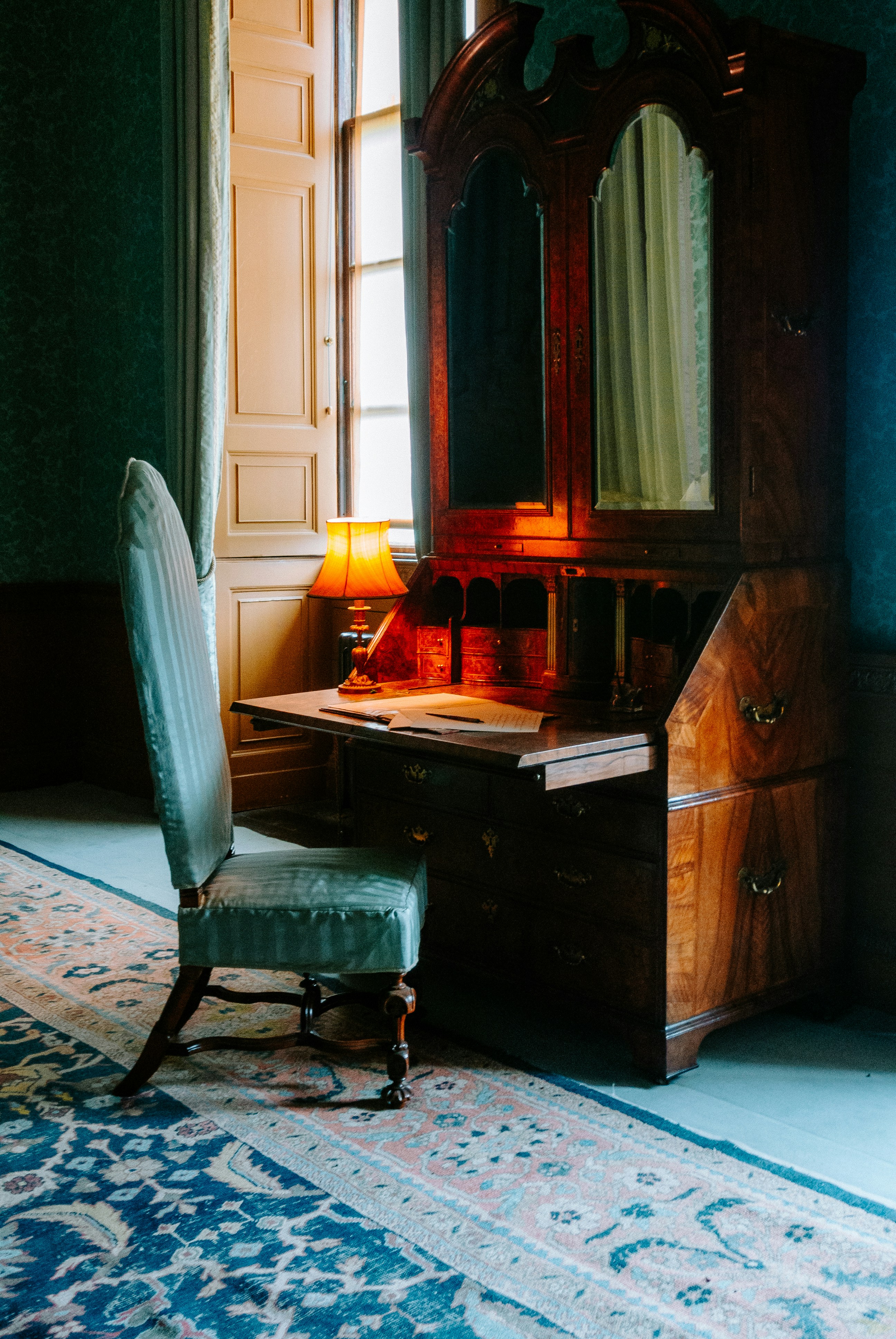 Antique writing desk with chair and lamp.