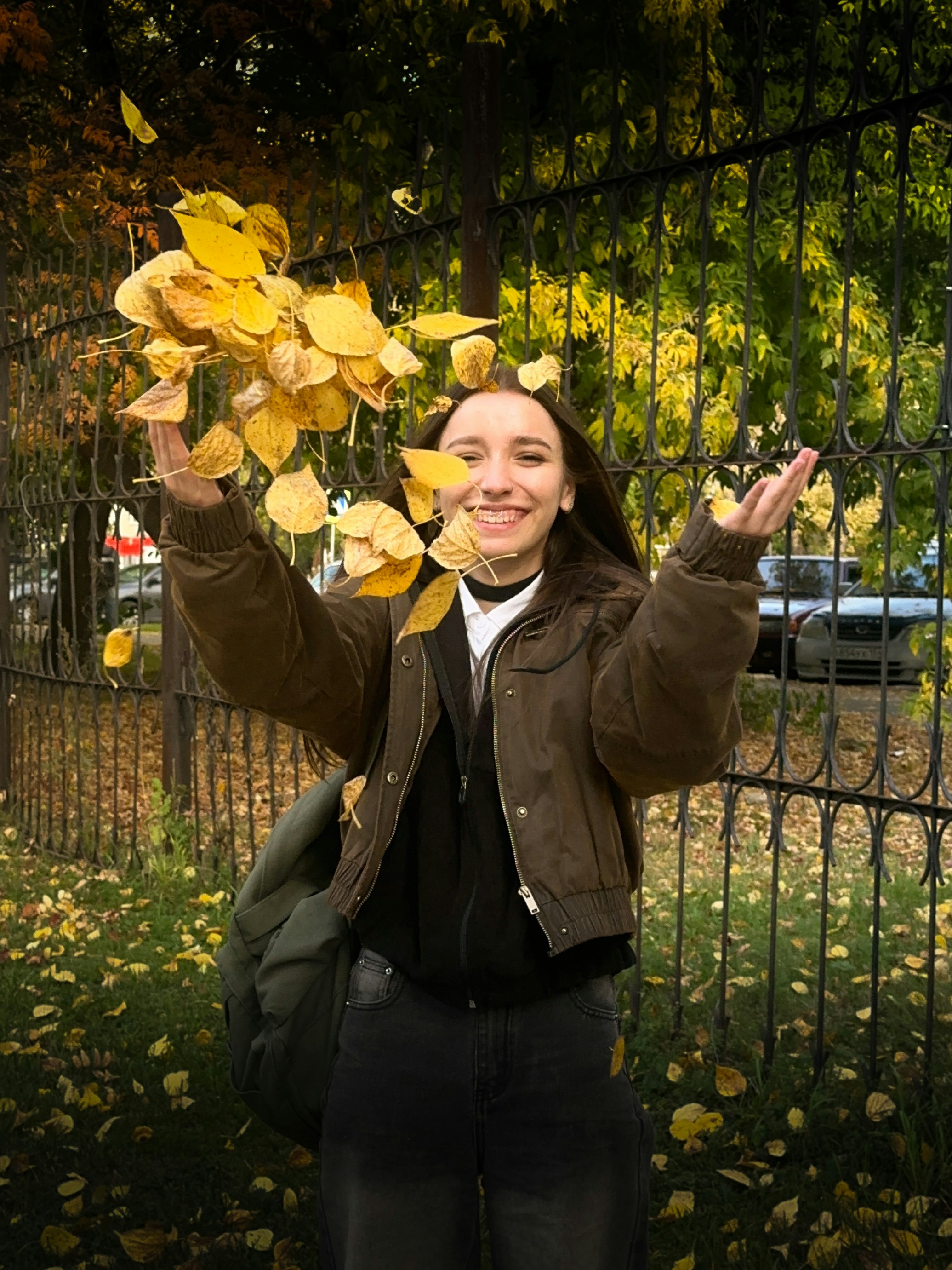Frau wirft gelbes Herbstlaub in die Luft