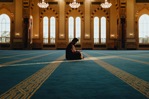 Man praying alone in a grand mosque with sunbeams