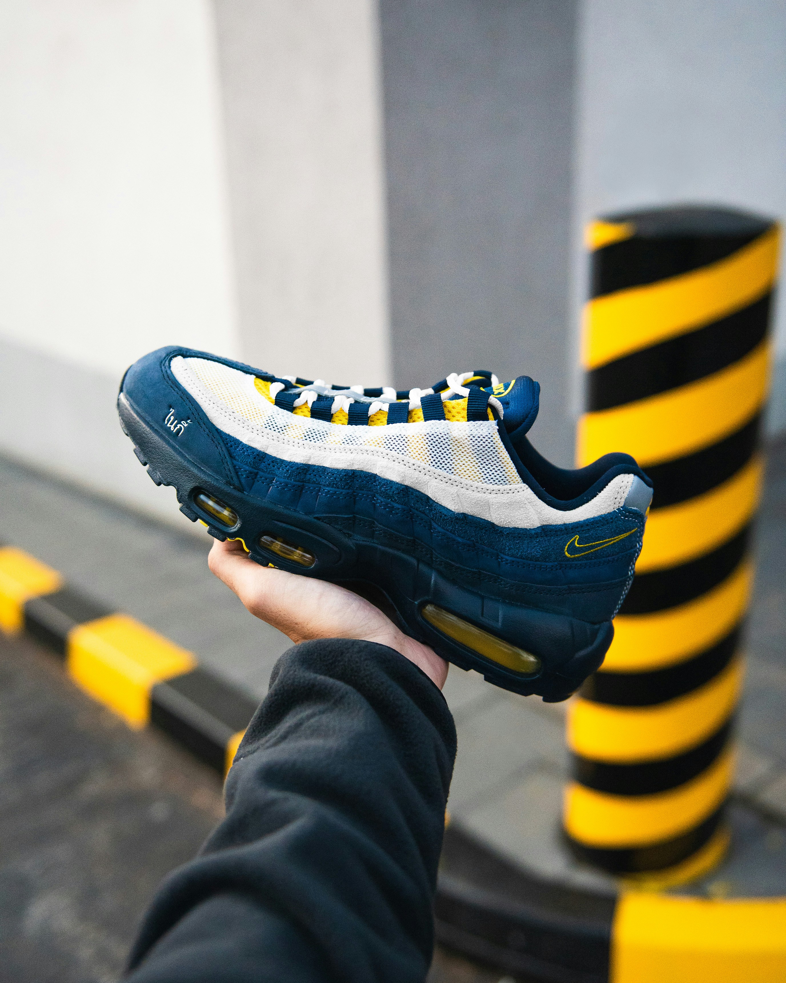 Hand holding a blue and yellow nike air max sneaker.