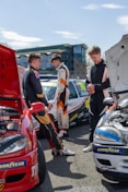Three young men in racing suits by cars